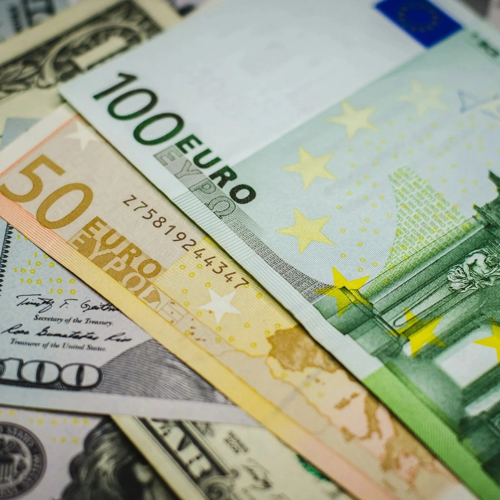 Billetes de diferentes monedas, incluyendo billetes de 100 dólares, 50 euros, 20 euros y 100 euros, con un fondo borroso de billetes de diferentes denominaciones.