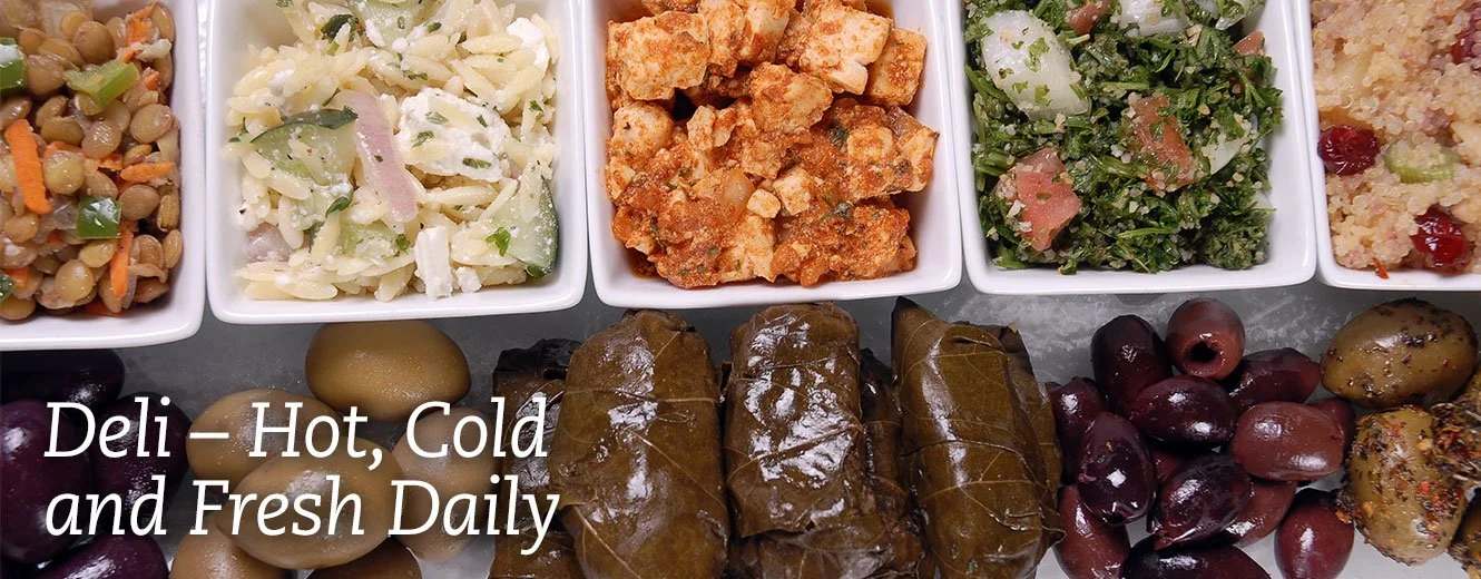 A variety of Mediterranean dishes including lentil salad, potato salad, grilled chicken, chopped kale salad, cornbread, olives, and stuffed grape leaves.