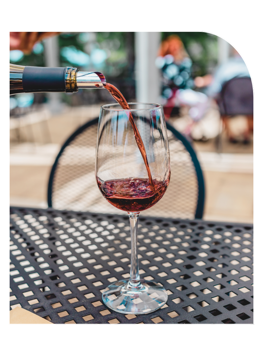 Red wine being poured into a wine glass outside on a black metal table at Shadow Ranch Vineyard.