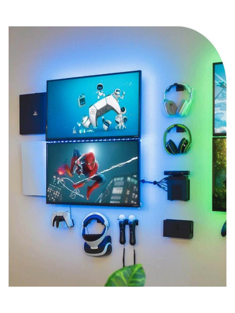 Arrangement of gaming equipment and wall mounts on the wall, including two monitors displaying animated characters, gaming headsets, controllers, a VR headset, PS5, PS$ and speakers illuminated with blue and green LED lights.