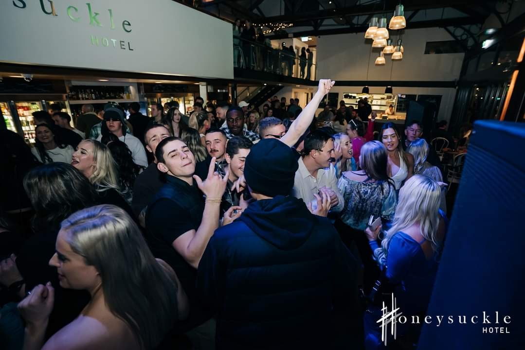 Crowd of people dancing and socializing at a lively party or event inside the Honeysuckle Hotel