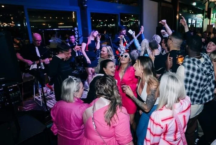 Group of women dancing and enjoying live music performance in a lively indoor venue at night.