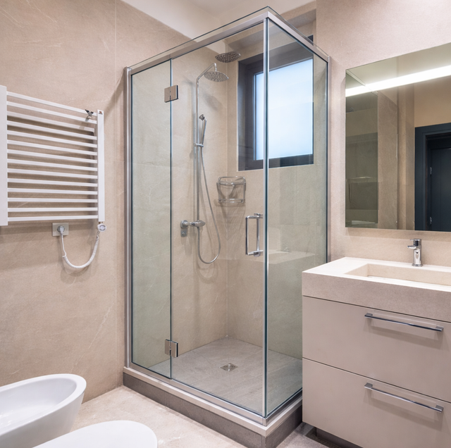 glass shower enclosure transition outlined by metal frame rails