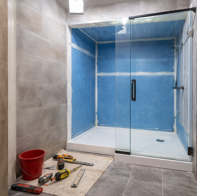 aged bathroom tub beside partly tiled shower walls