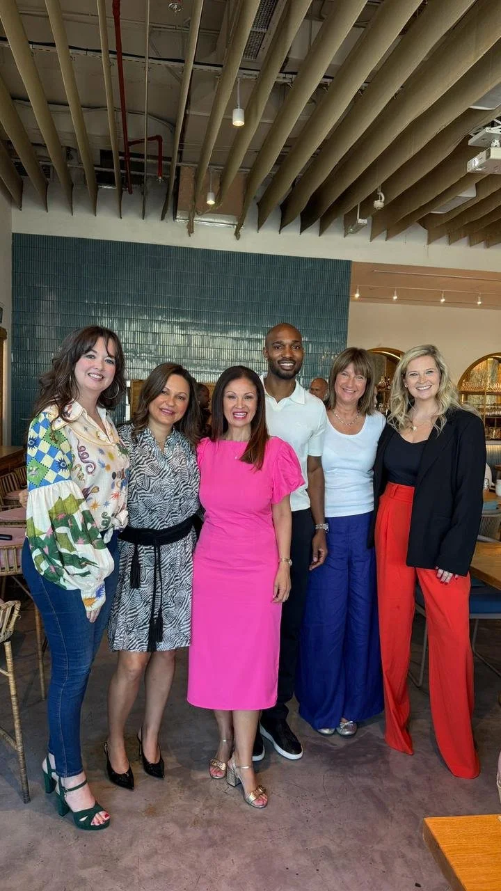 Six women and one man standing together inside a modern restaurant, smiling for the photo.