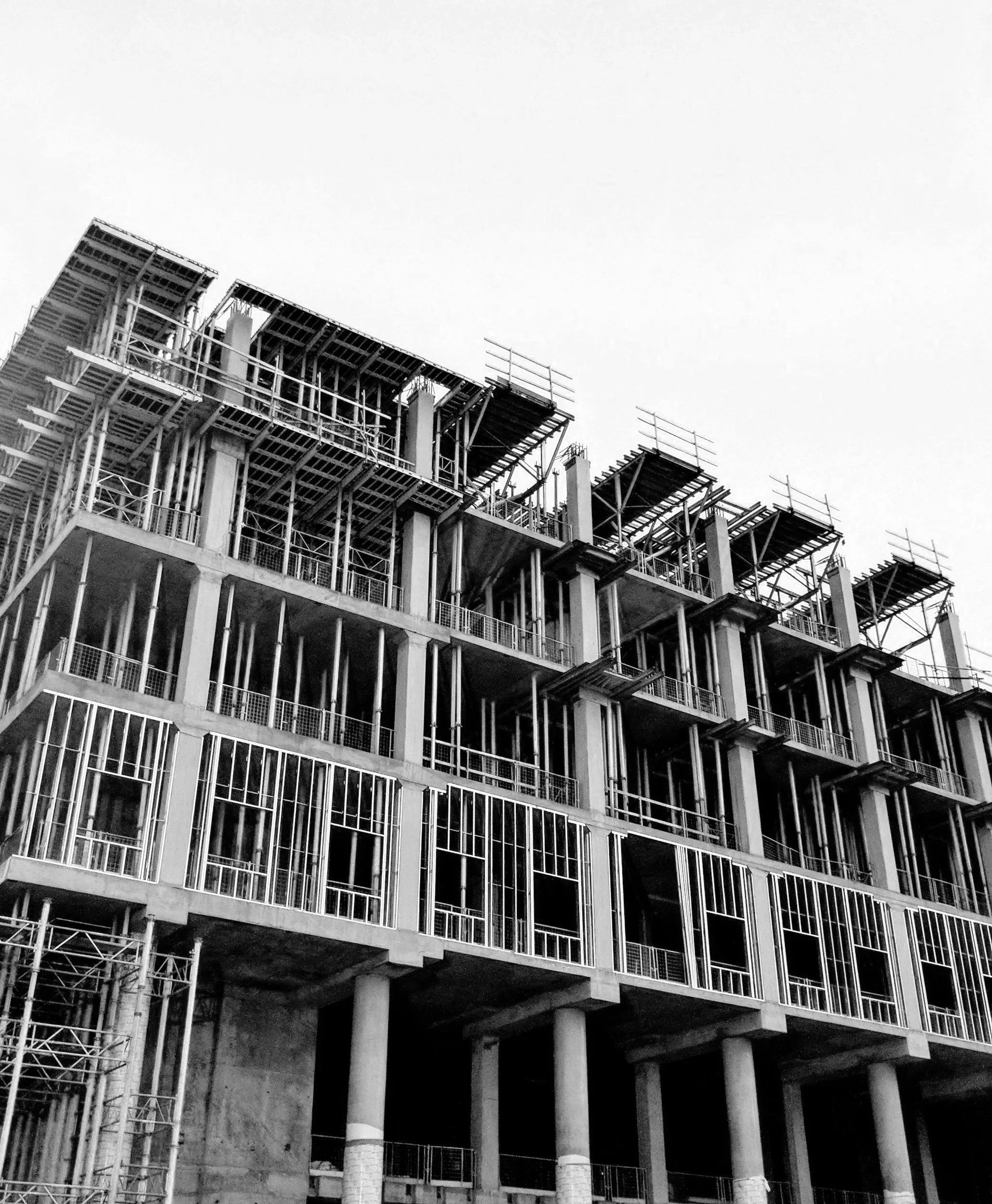 Black and white photo of a multi-story building under construction with scaffolding and exposed structural elements.