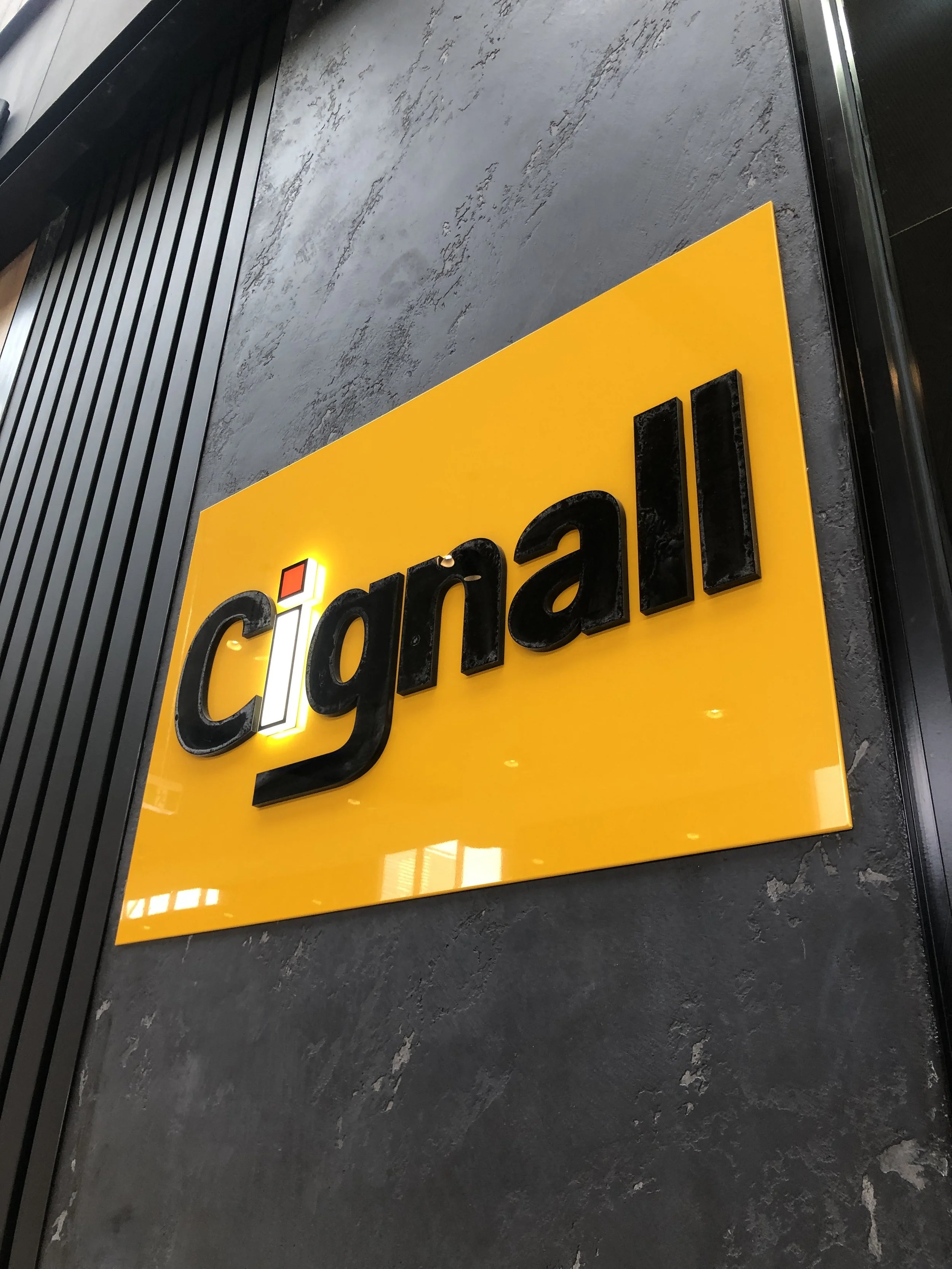 Close-up of a black sign with yellow background, displaying part of the word 'cial' in black 3D letters, likely part of a larger word.