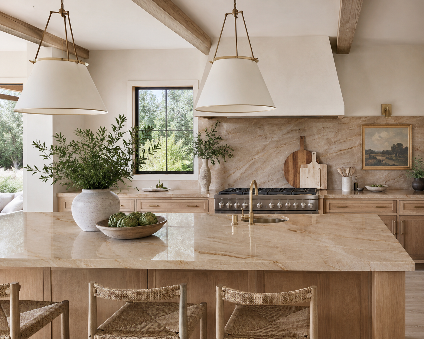 A bright, airy kitchen with a large beige marble island, wooden chairs, green plants in white vases, a window showing greenery outside, a stove, and various kitchen utensils and decor.