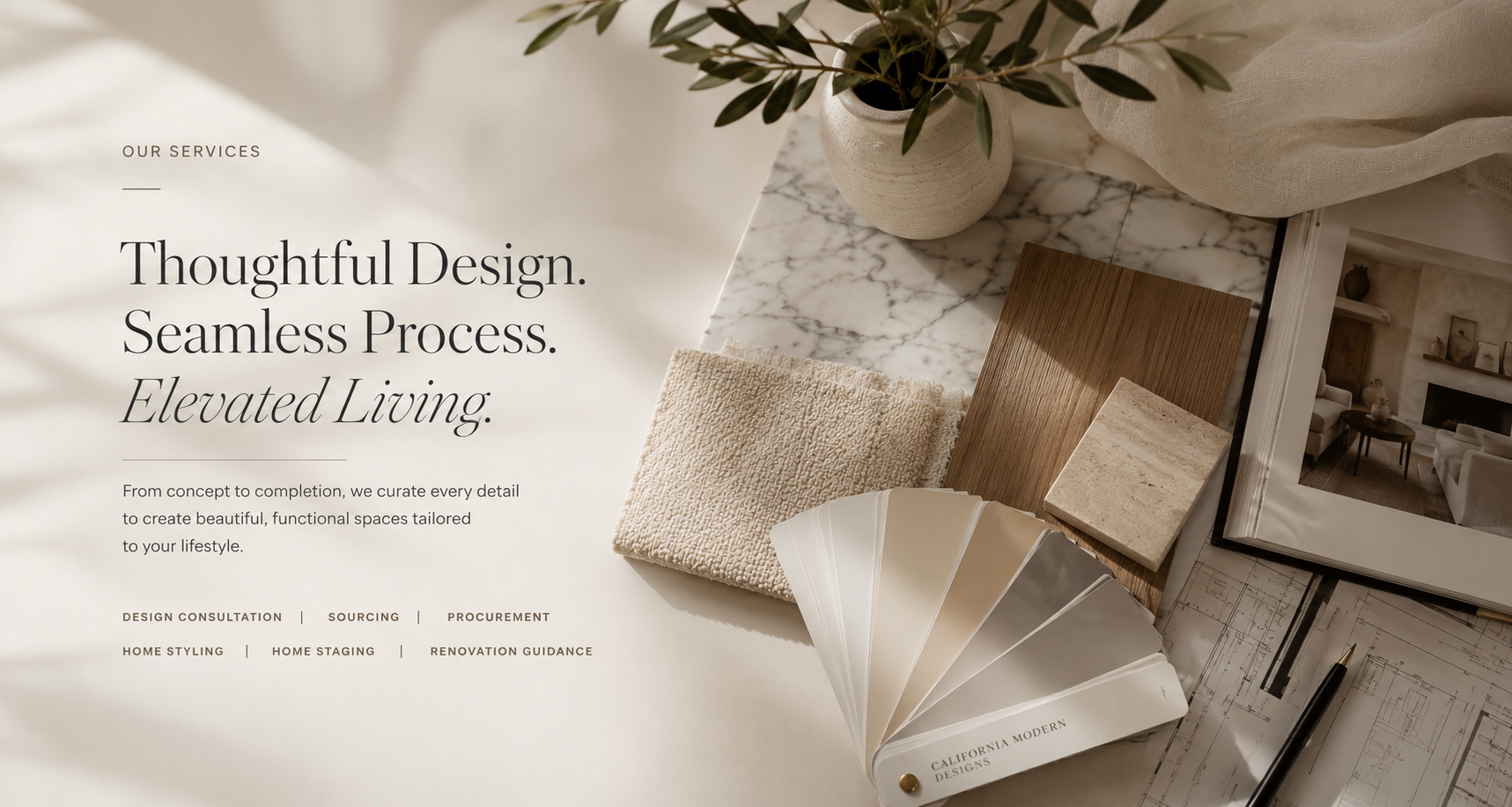 A website homepage showcasing interior design services with a marble tabletop, a potted plant, fabric samples, wood samples, color swatches, a design magazine, and architectural plans. The text emphasizes thoughtful design, seamless process, and elevated living.