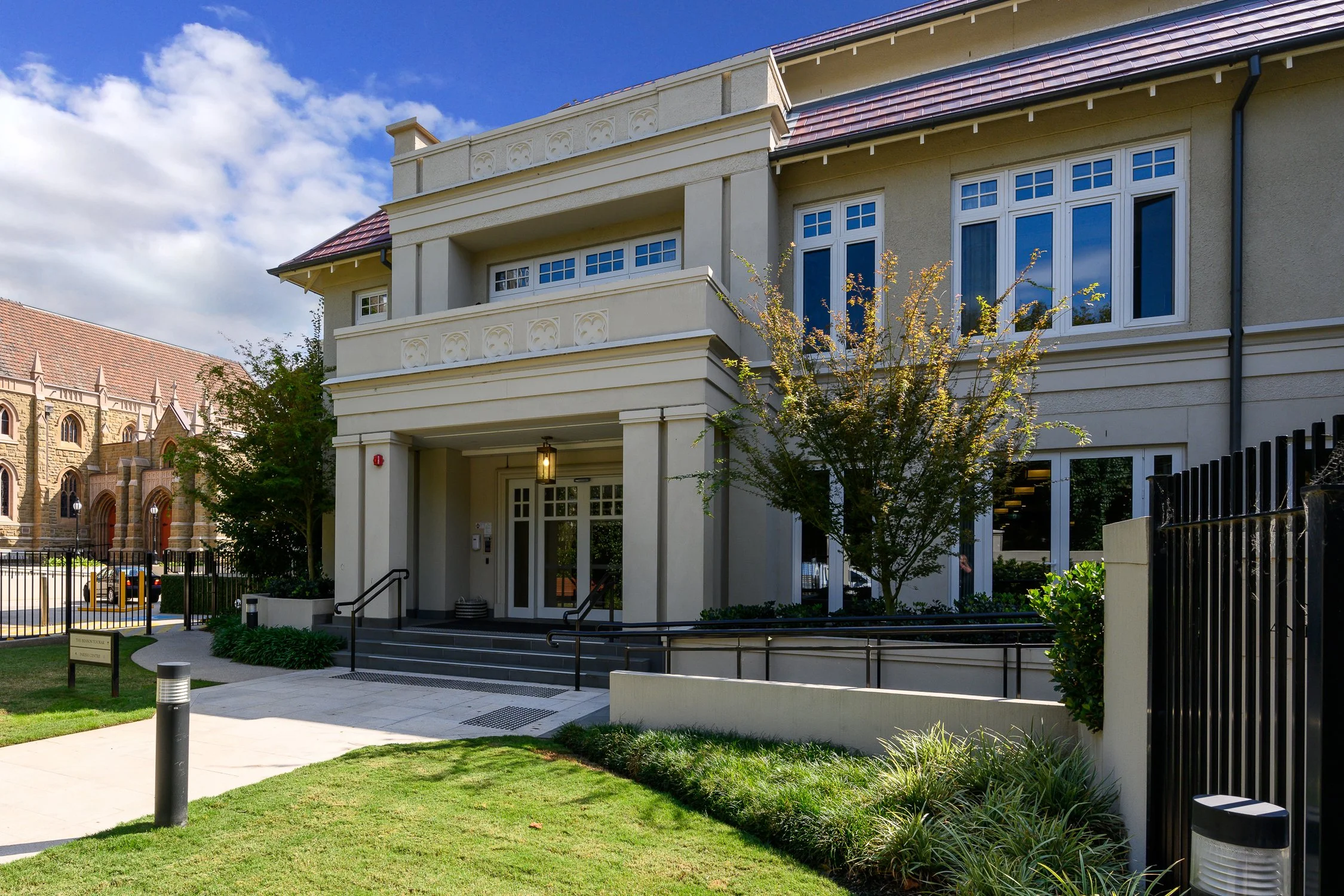 Entrance view of luxury multi-story retirement apartments surrounded by lush green trees, with secure underground parking and lift access.