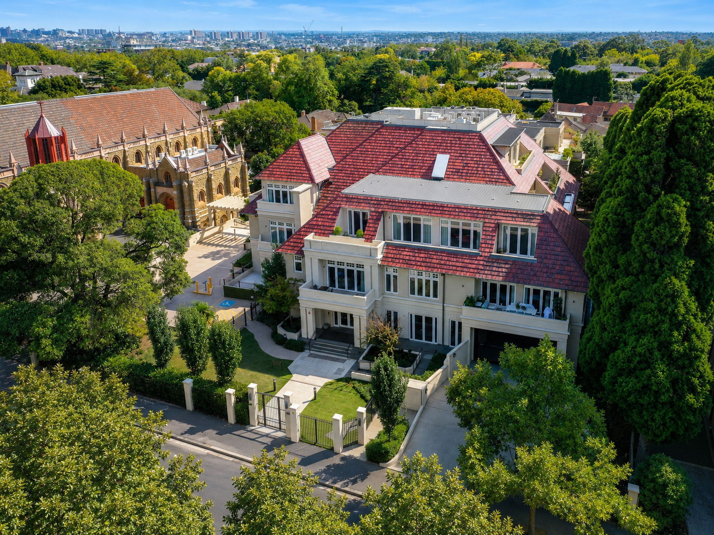 An aerial view of The Benson Toorak and St Peter's Toorak, luxury multi-story retirement apartments surrounded by lush green trees, with a gated front entrance secure underground parking.