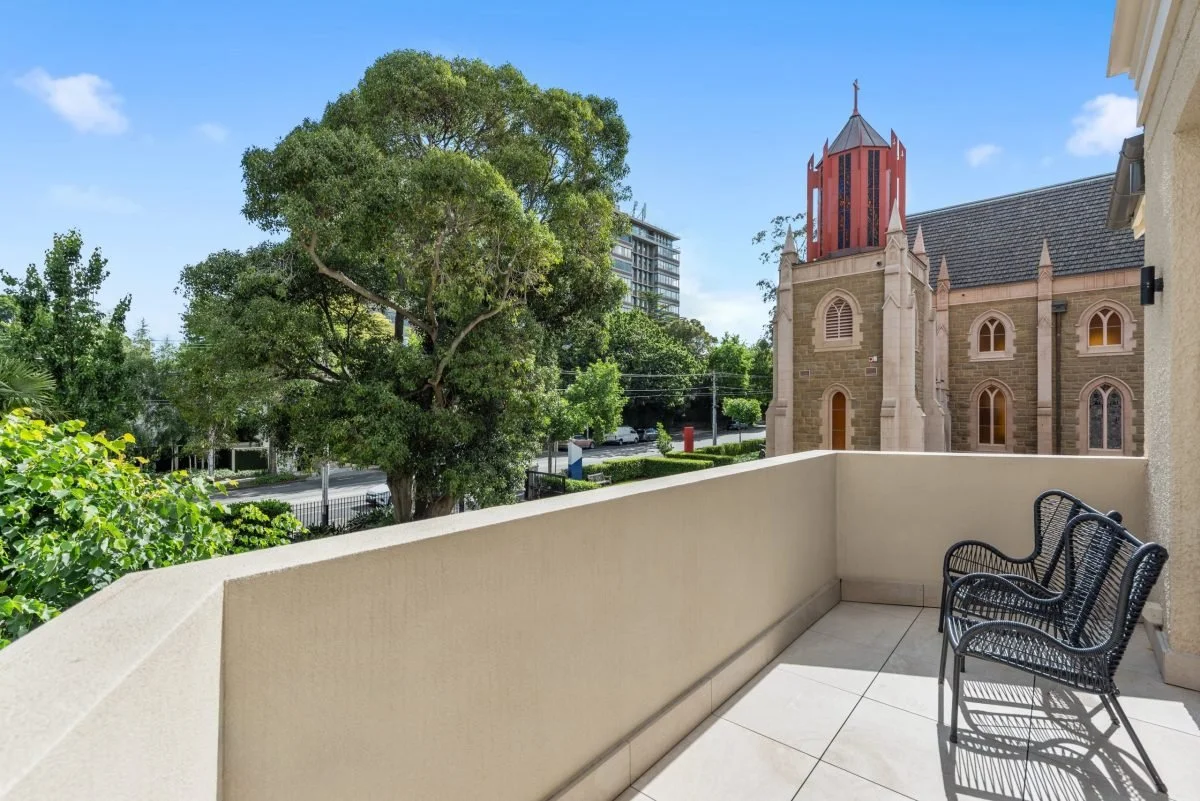 View from a balcony showing trees, St Peter's Toorak church on a sunny day.