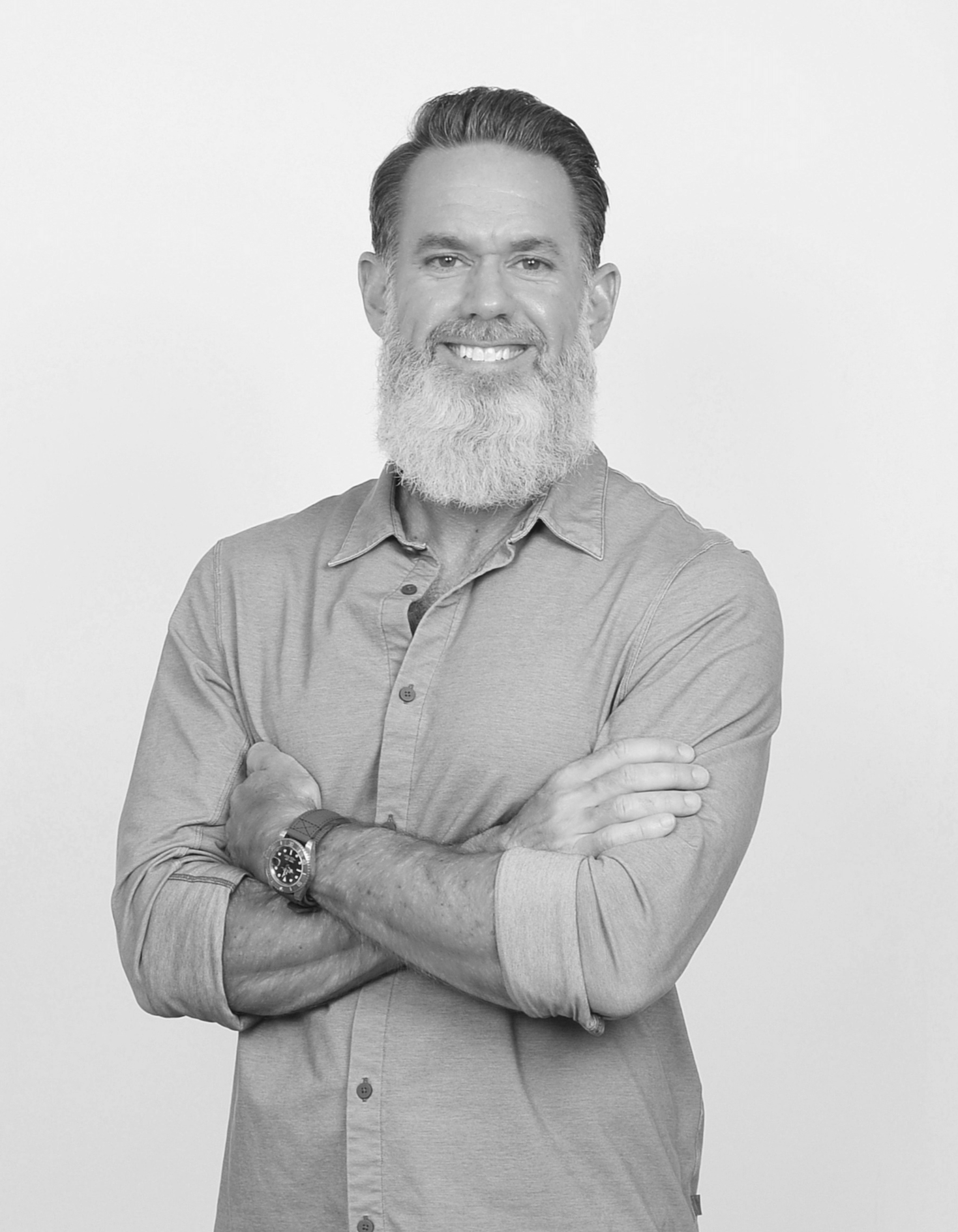 Black and white photo of founder Matthew Thrasher, wearing a button-up shirt, with arms crossed, against a plain background.