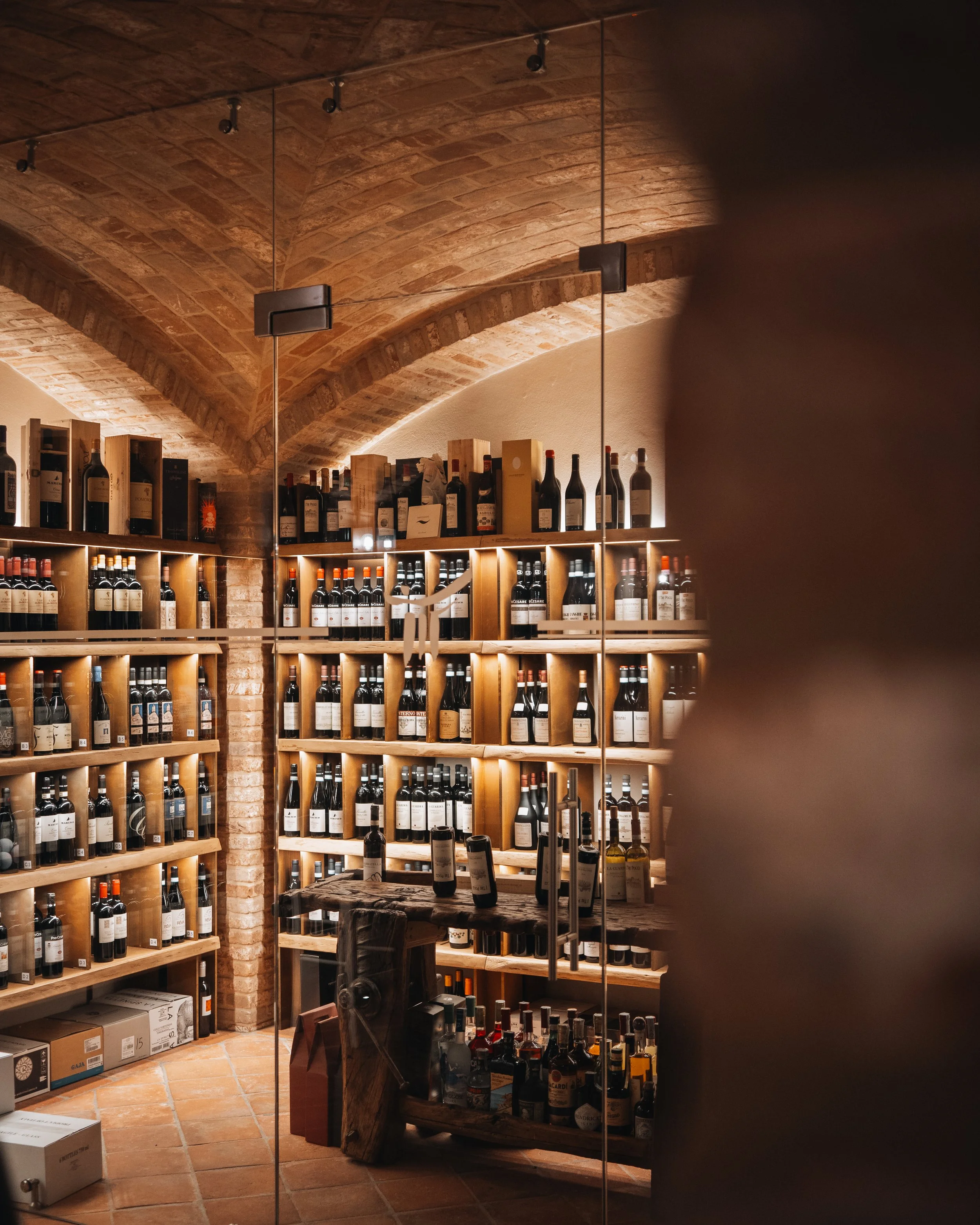 Scaffale di vini in una cantina con soffitto a volta in mattoni.