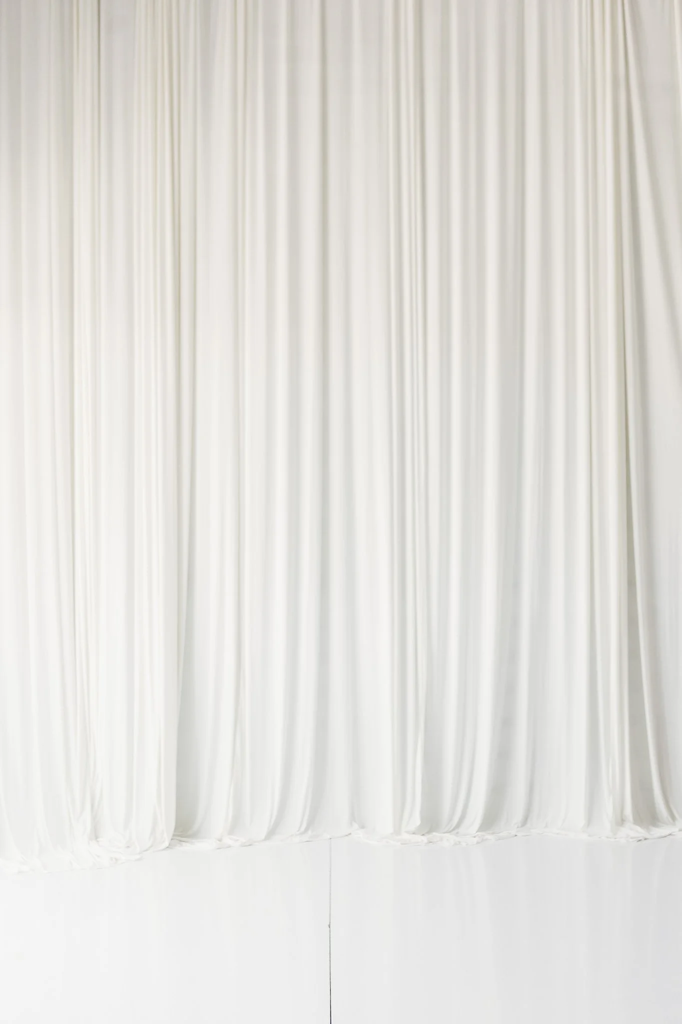 White stage curtain hanging from a curtain rod.