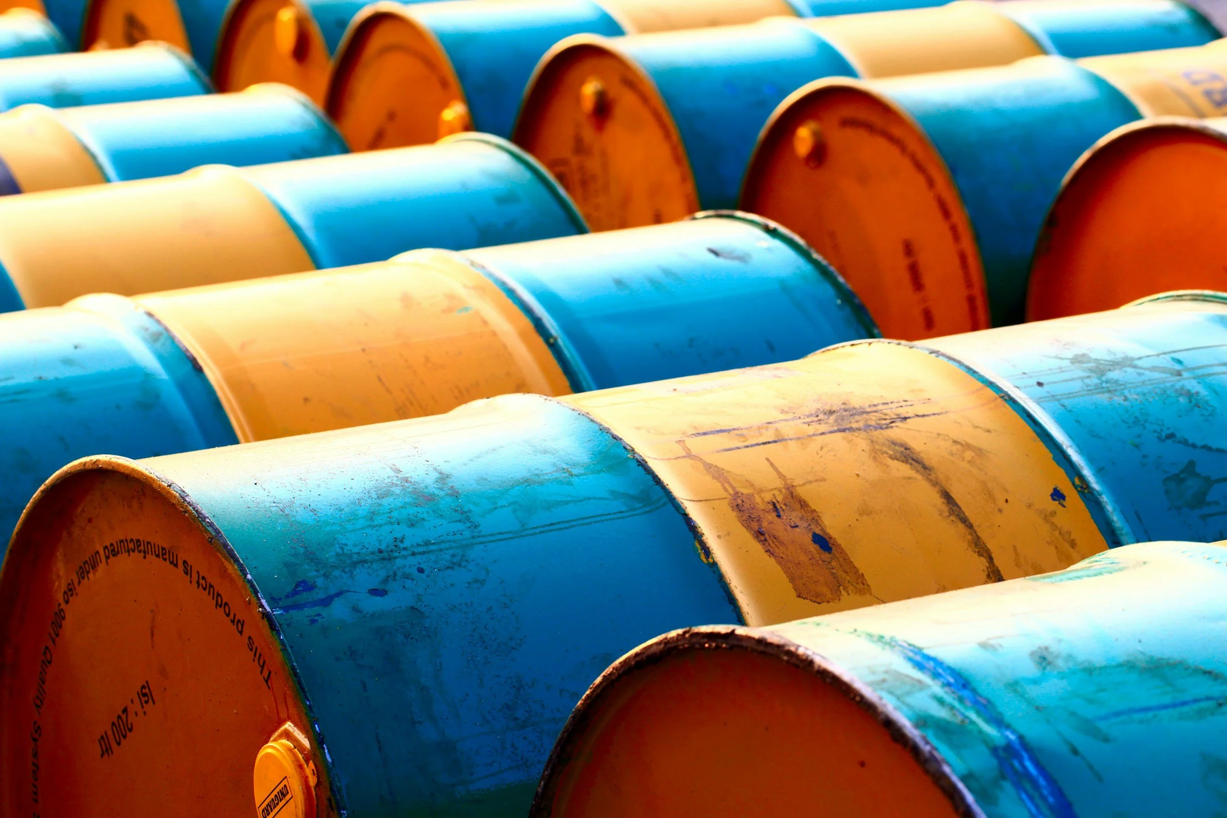 A close-up view of orange and blue painted barrels or drums arranged in rows.