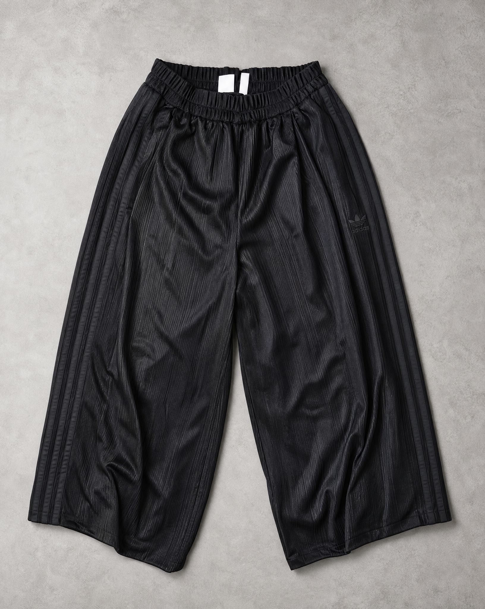 Generated with Kive.ai - Black pleated trousers make a flat lay of adidas trousers where you see the logo and three stripes.png