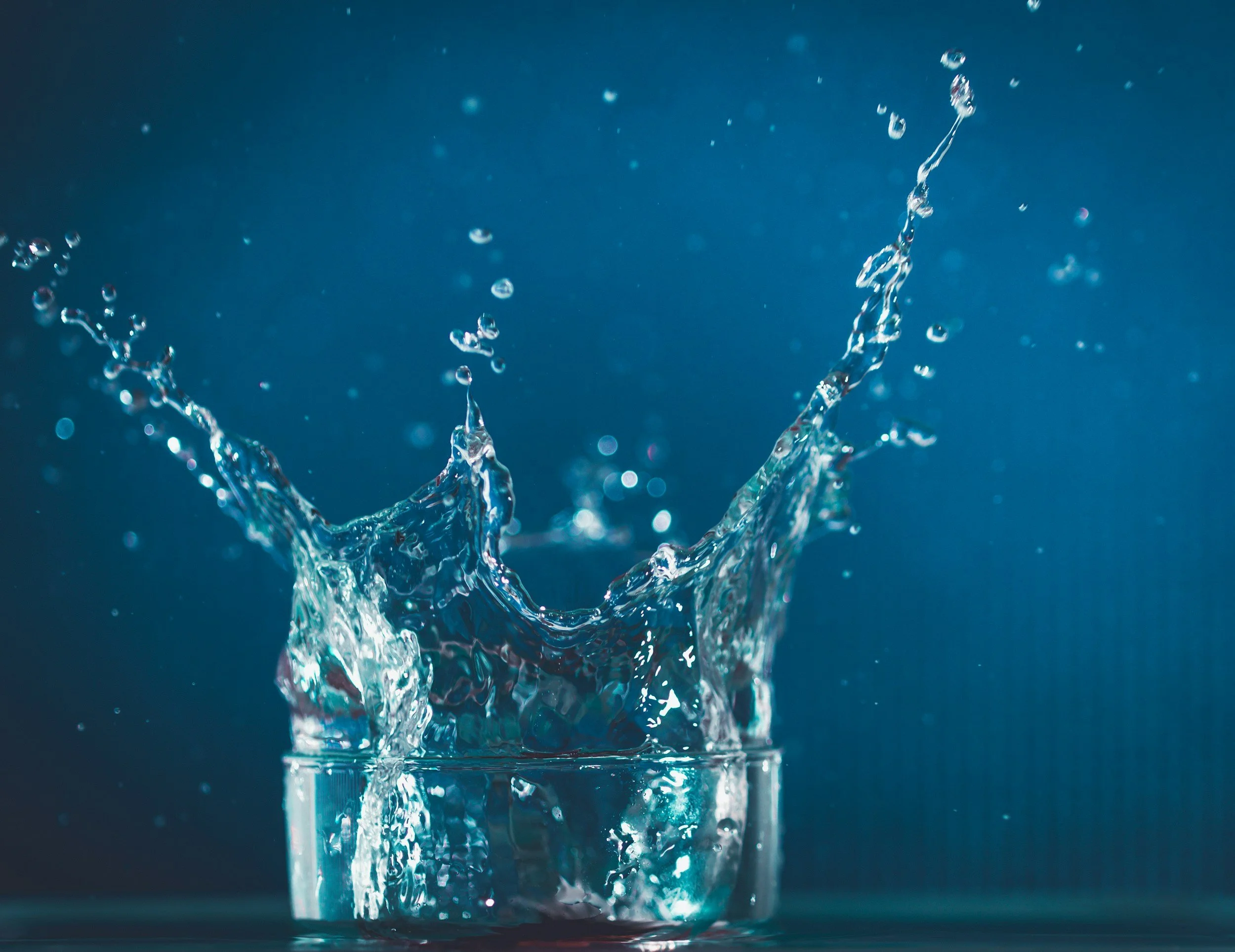 Close-up of water splashing and droplets suspended in midair against a dark background.