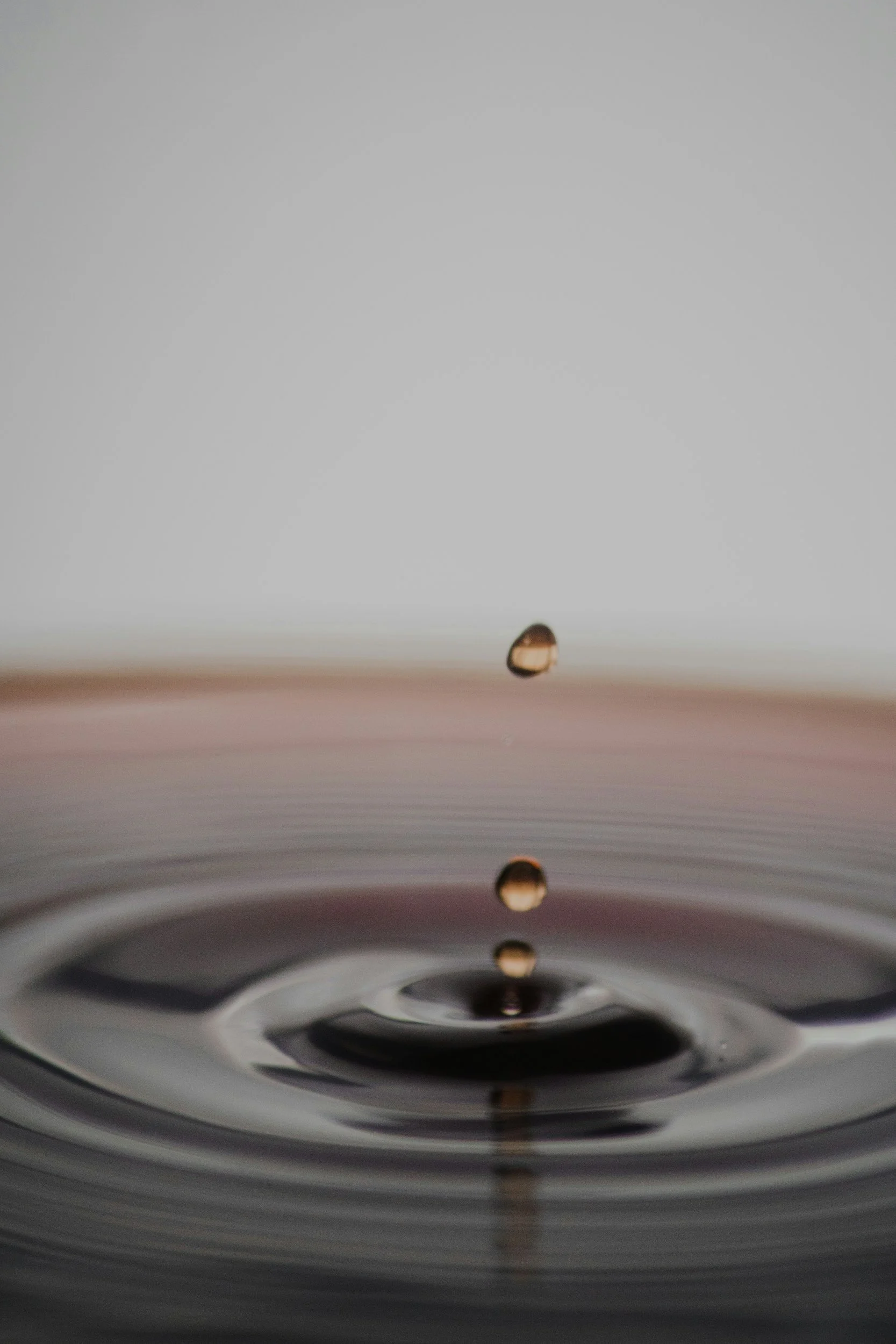 Close-up of a water droplet falling into a body of water, creating ripples.