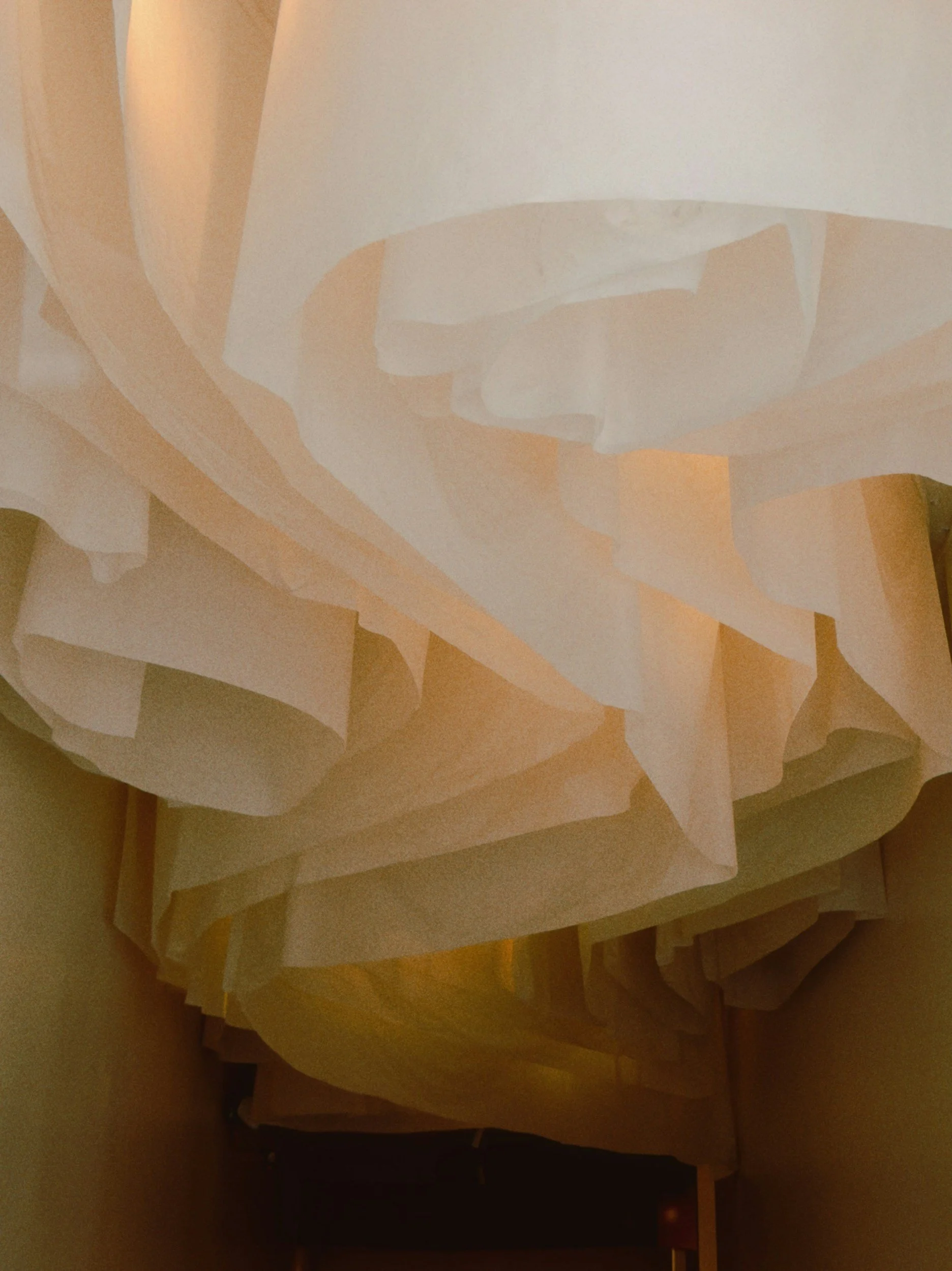 Close-up of layered cream-colored tissue paper or fabric with a soft, flowing appearance.