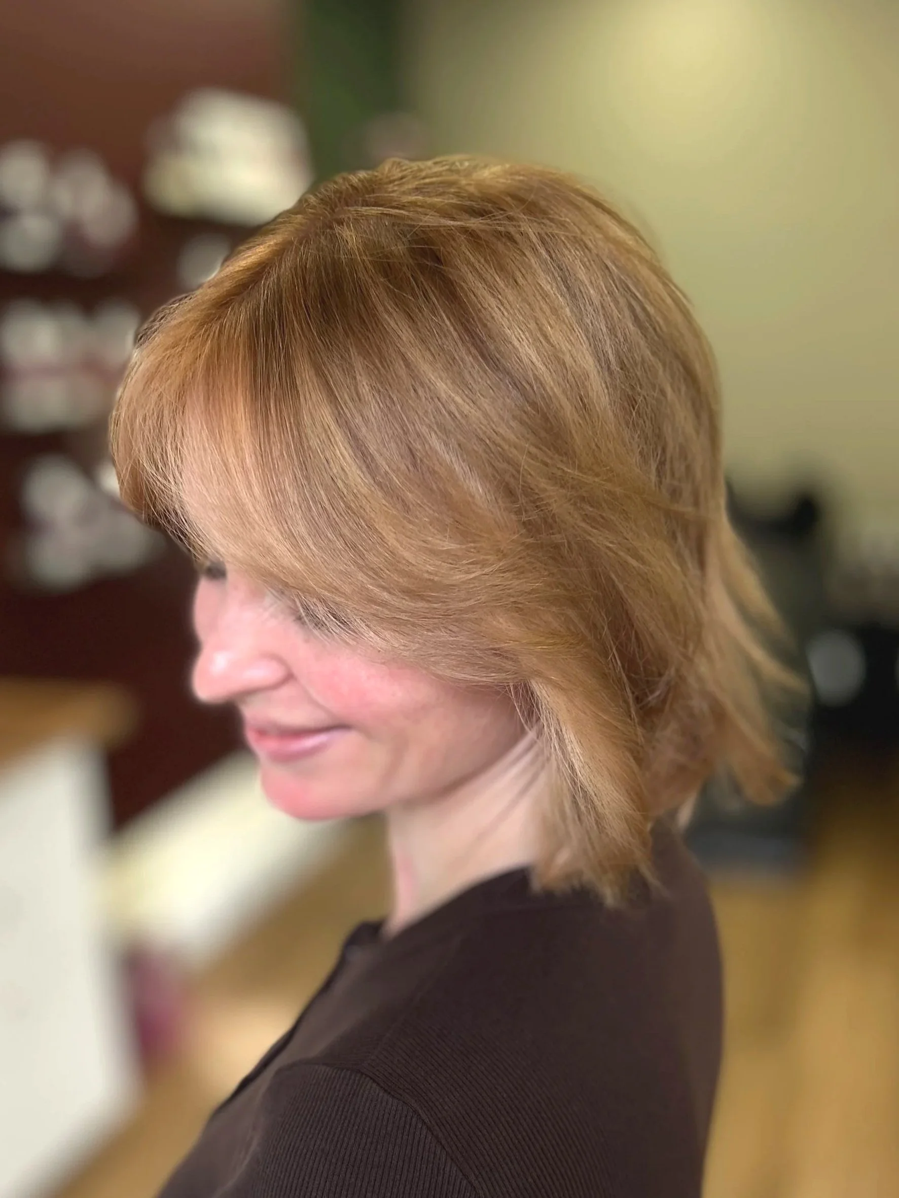 Side profile of a woman with styled, reddish-blonde hair wearing a black top.
