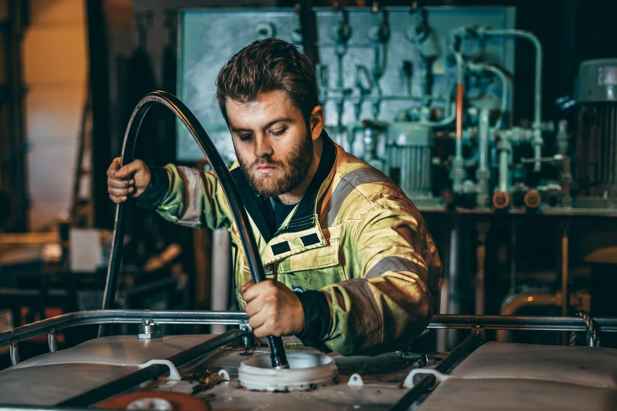 Service team, saunesmarka, dimo service. Hosedoctor parker. En mann i arbeidstøy jobber med en maskindel i en verkstedsetting.