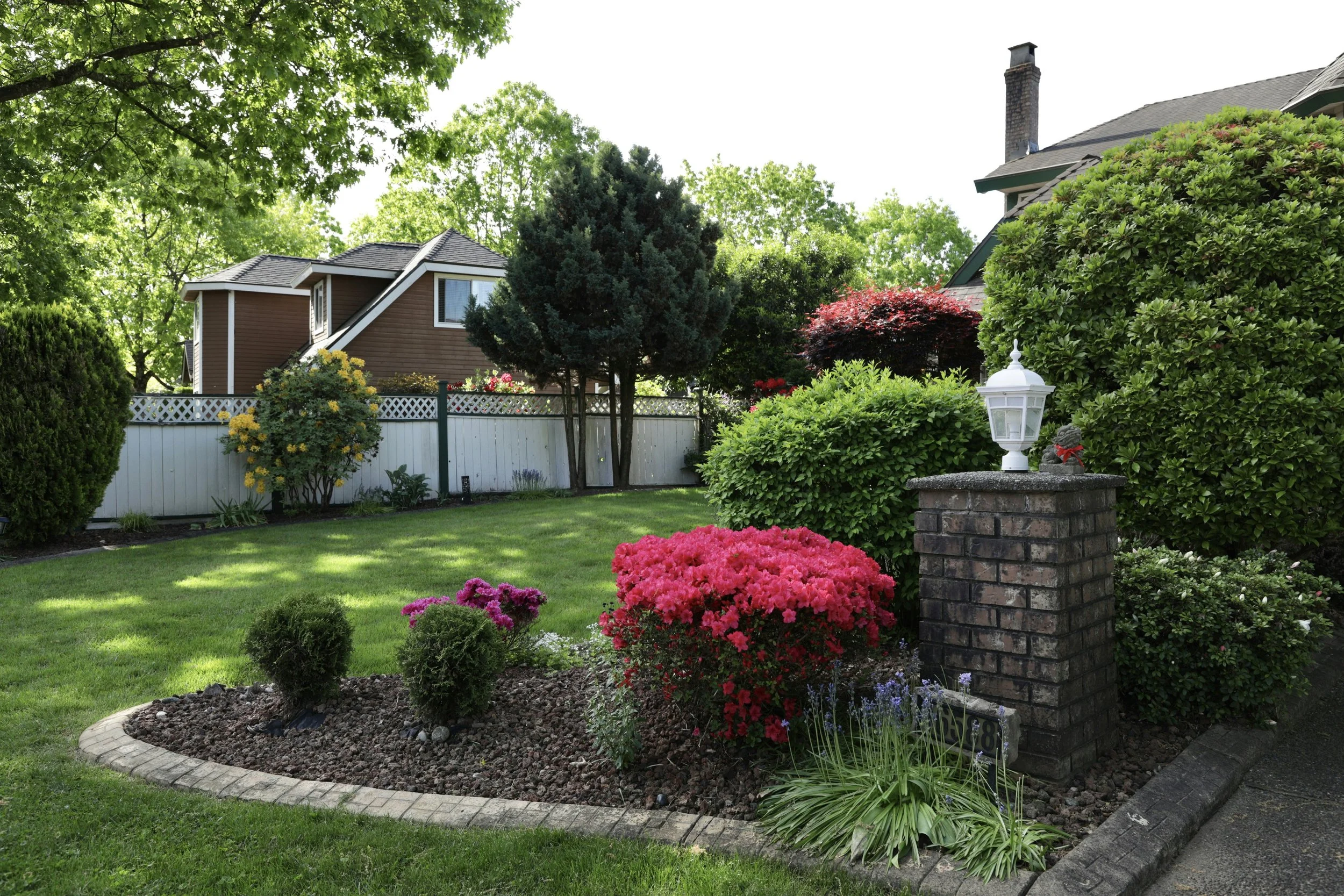 Well-maintained backyard garden with colorful flowers, mulch beds, green lawn, and house, section 03: Mulch & Pine Straw installation.