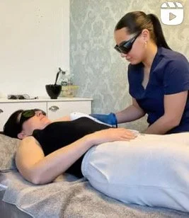A woman lying face down on a massage table being attended to by a therapist in a blue uniform.