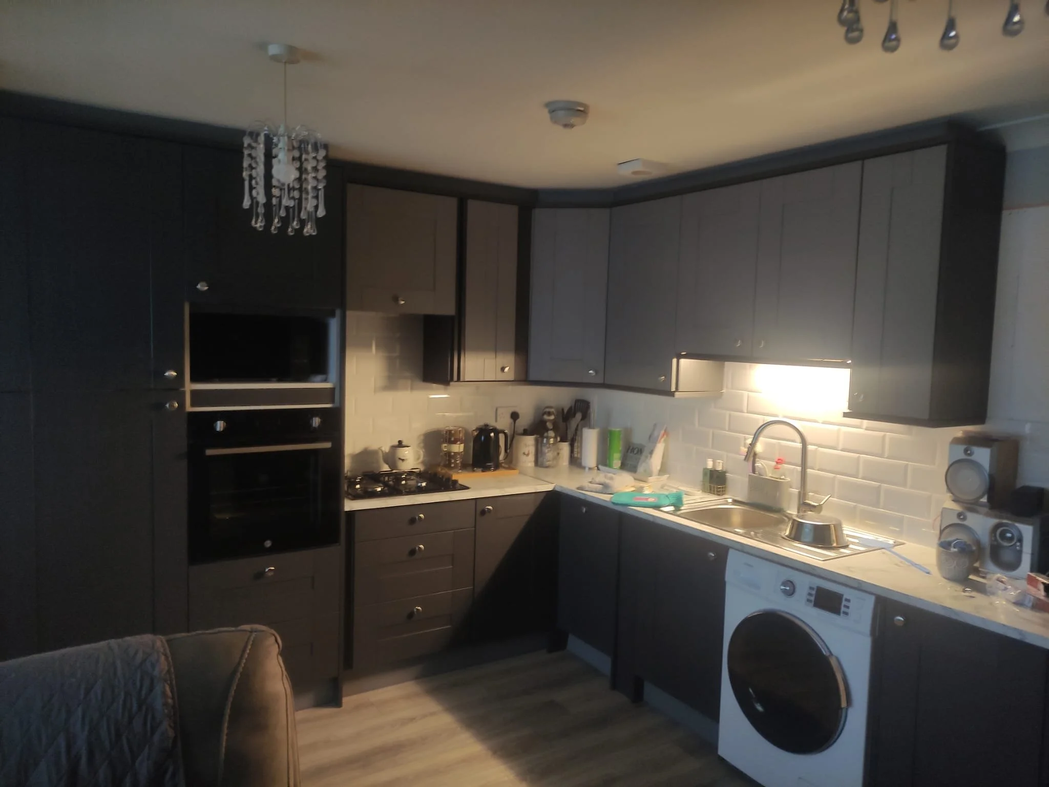 Kitchen with dark cabinets, white tile backsplash, white fridge, stove, microwave, and various small appliances on the counter.