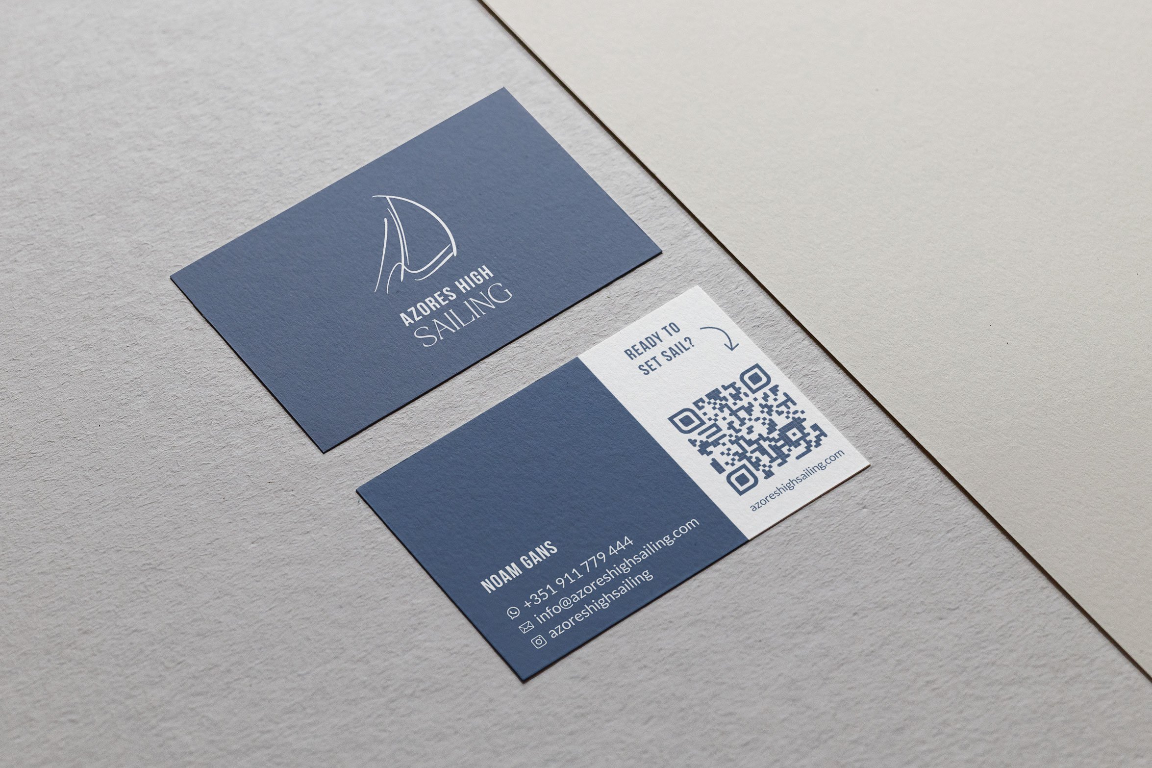 Visitenkarte mit dem Logo eines Segelschiffs, Text 'AZORES HIGH SAILING', QR-Code, Kontaktinformationen und Website, auf grauem Hintergrund.
