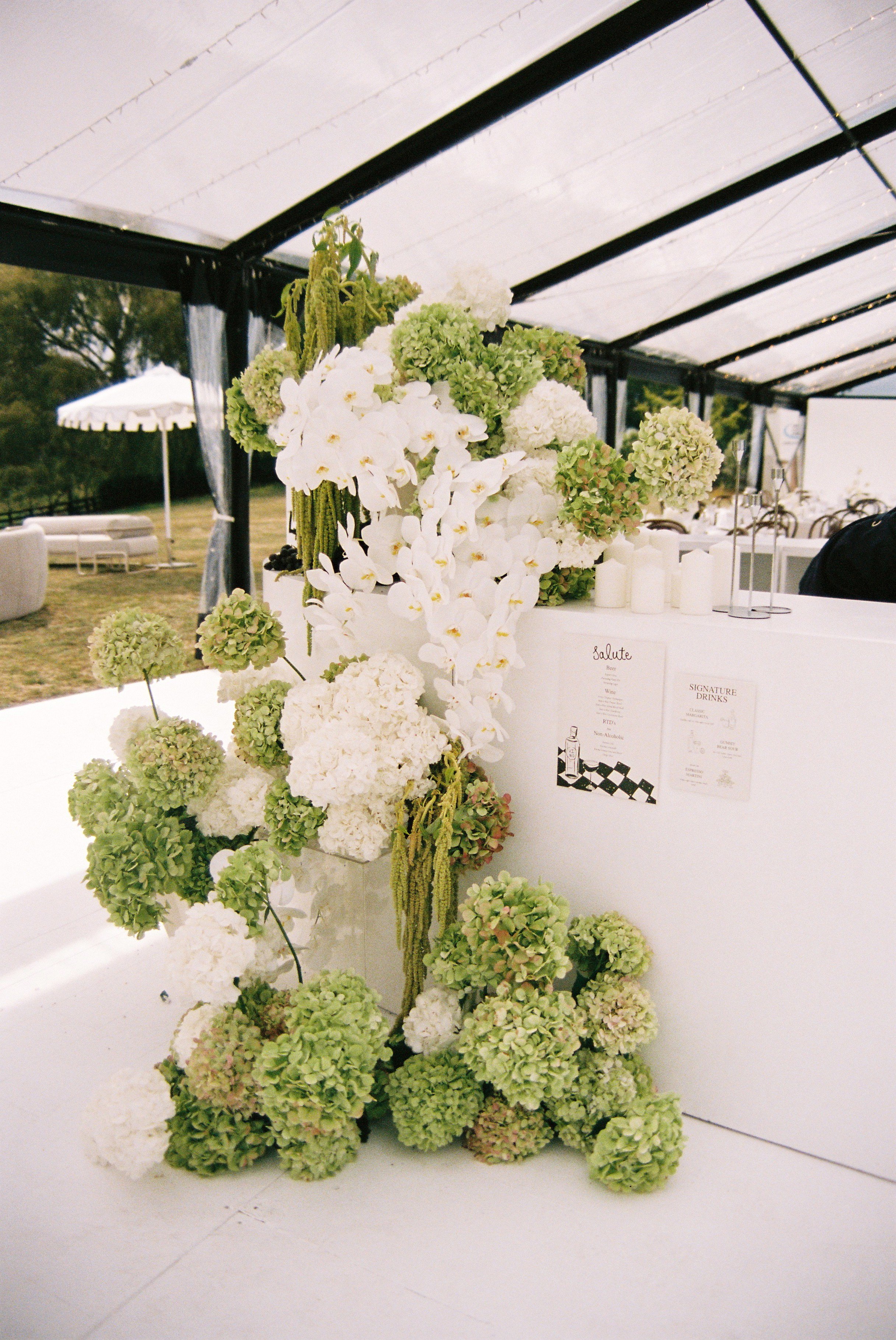 Large bar flowers installation for wedding reception in white and green hydrangeas, phaleonopsis orchids and amaranthus
