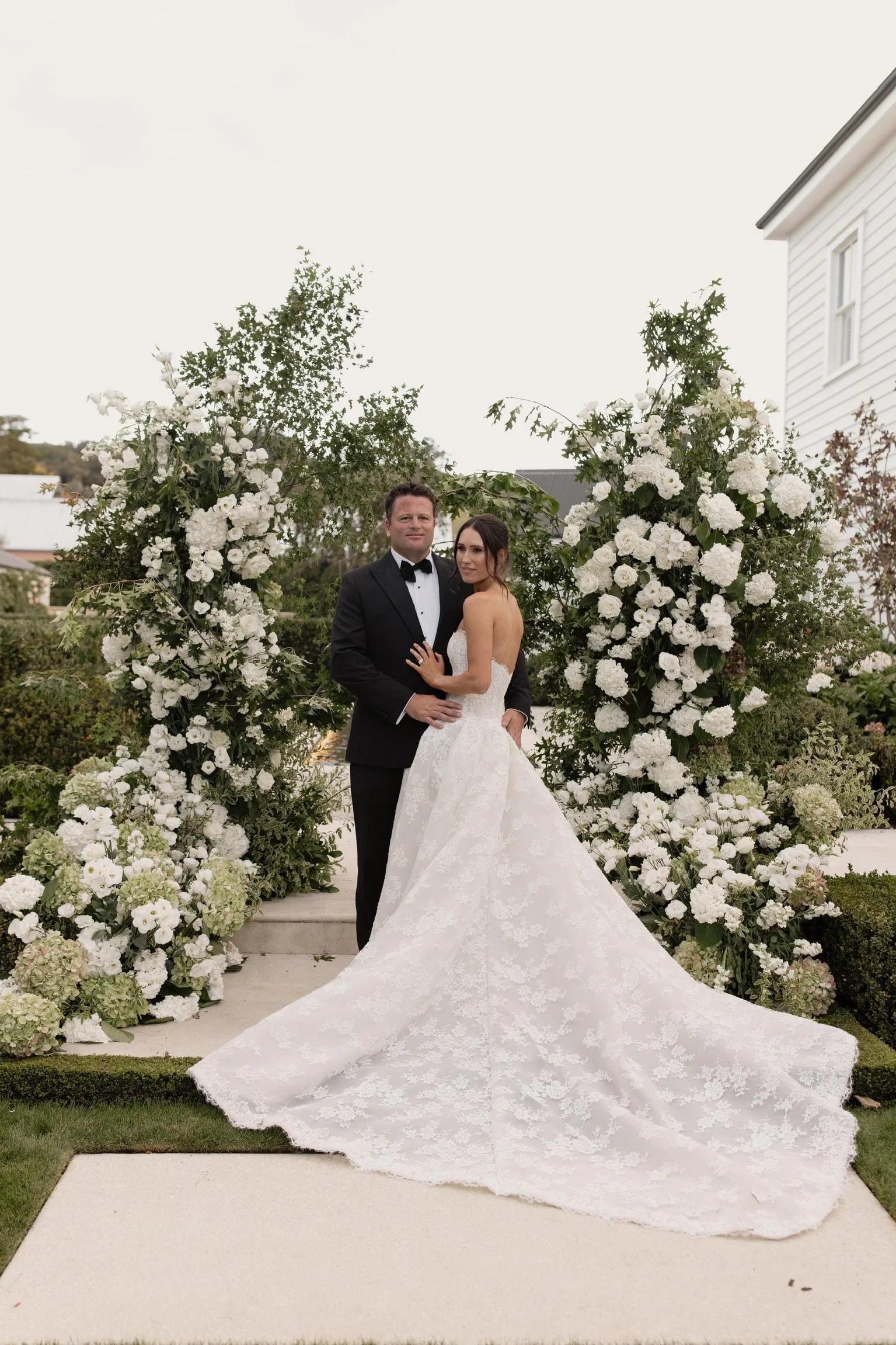 Large ceremony floral backdrop in and green florals with bride and groom in front
