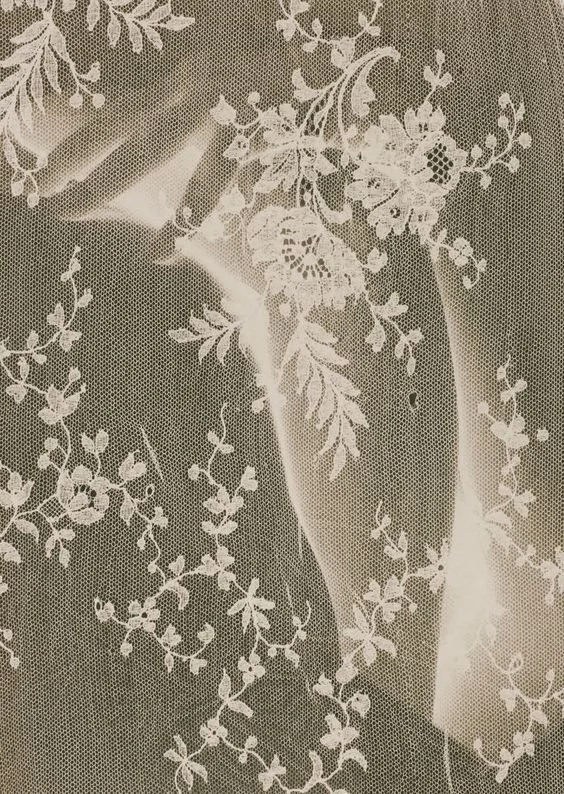 Vieux livre avec une couverture en tissu, ornée de broderies florales blanches.