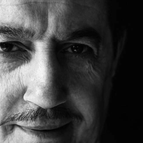 Ritratto di un uomo con espressione serena e senza capelli, con dettagli evidenti del viso in bianco e nero.