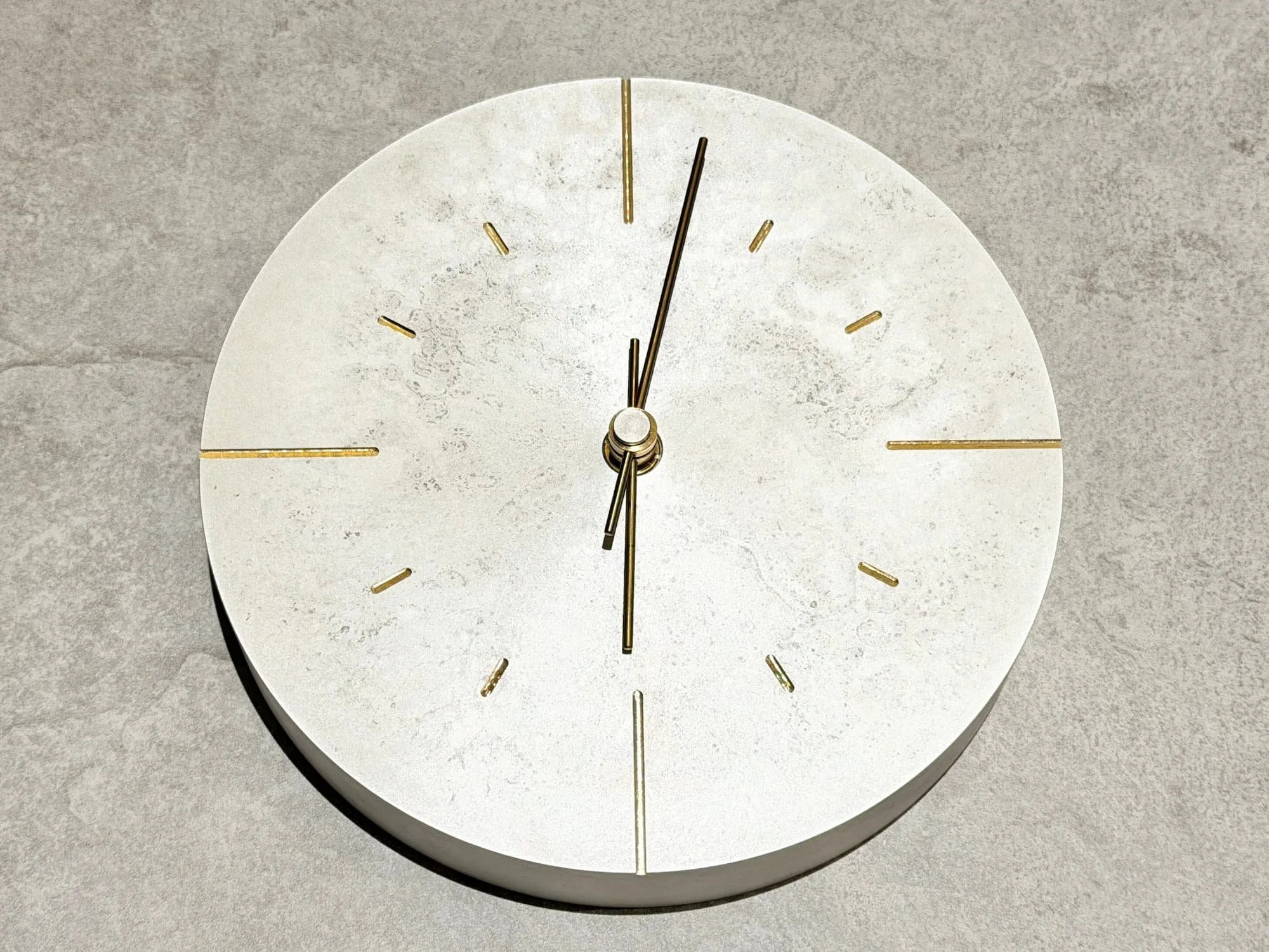 A white, round wall clock hangs on the wall, showing 11:55.