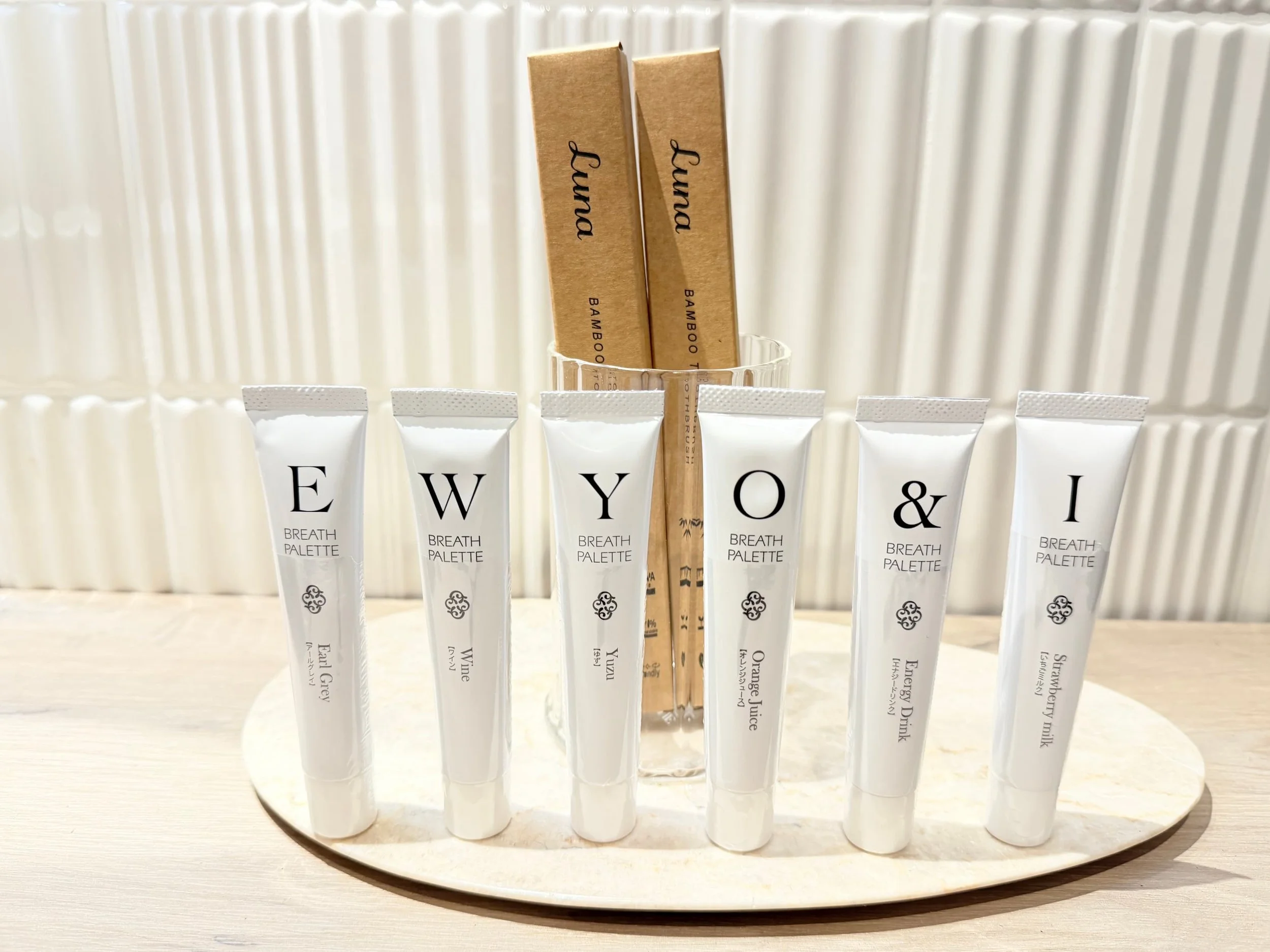 Beauty tubes and wooden sticks lined up on a display against a white background.