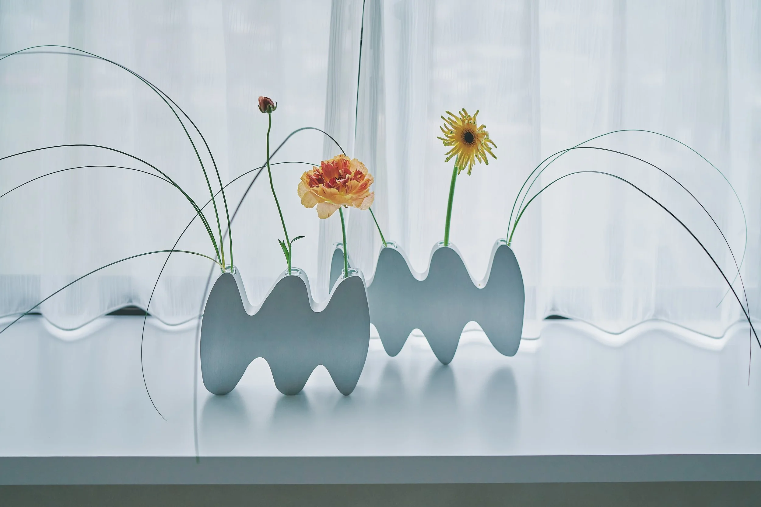 A row of glass vases decorated with colorful flowers is arranged against a white background.