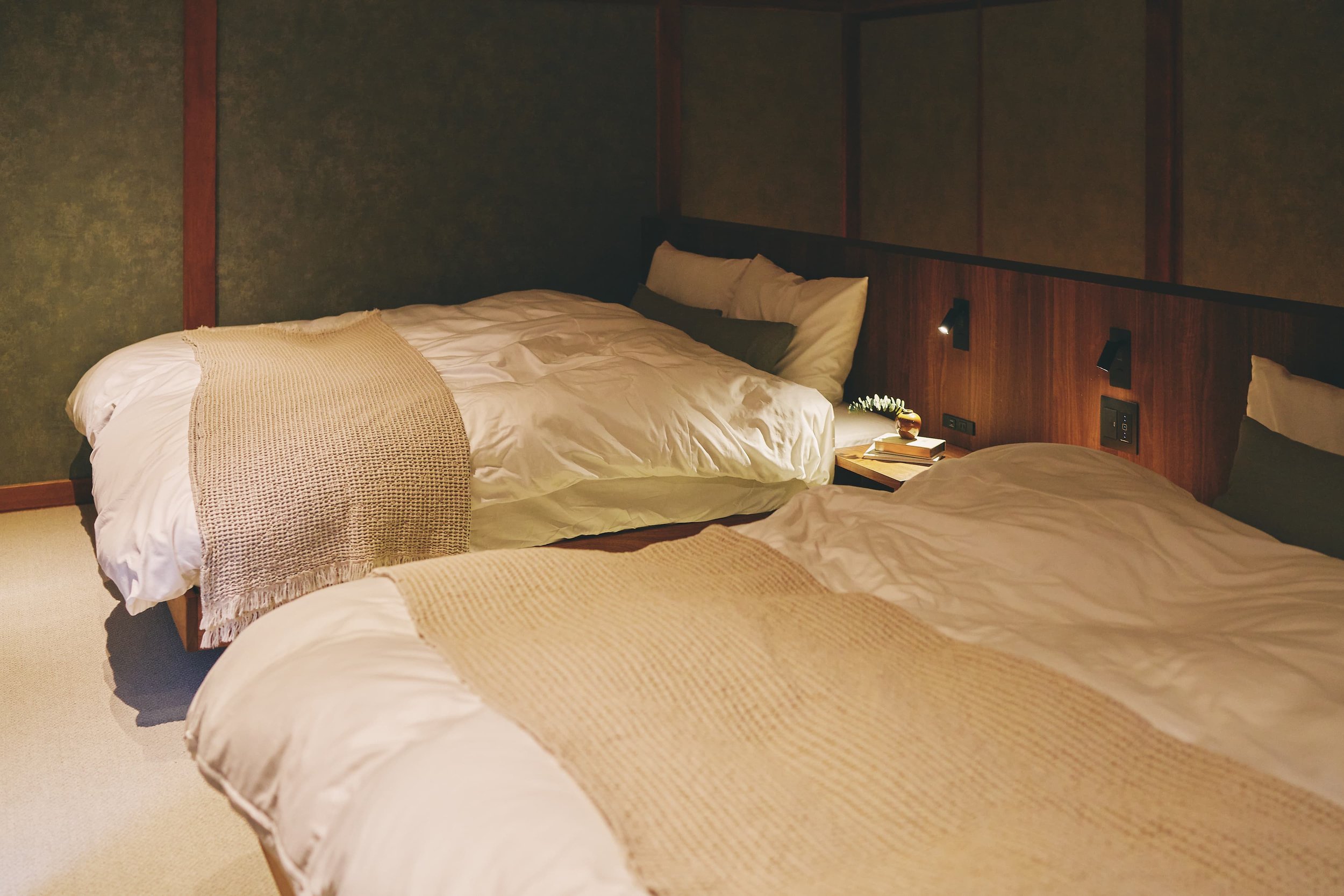 The photo of the bedroom shows two beds with dark wood headboards, along with pillows and blankets.