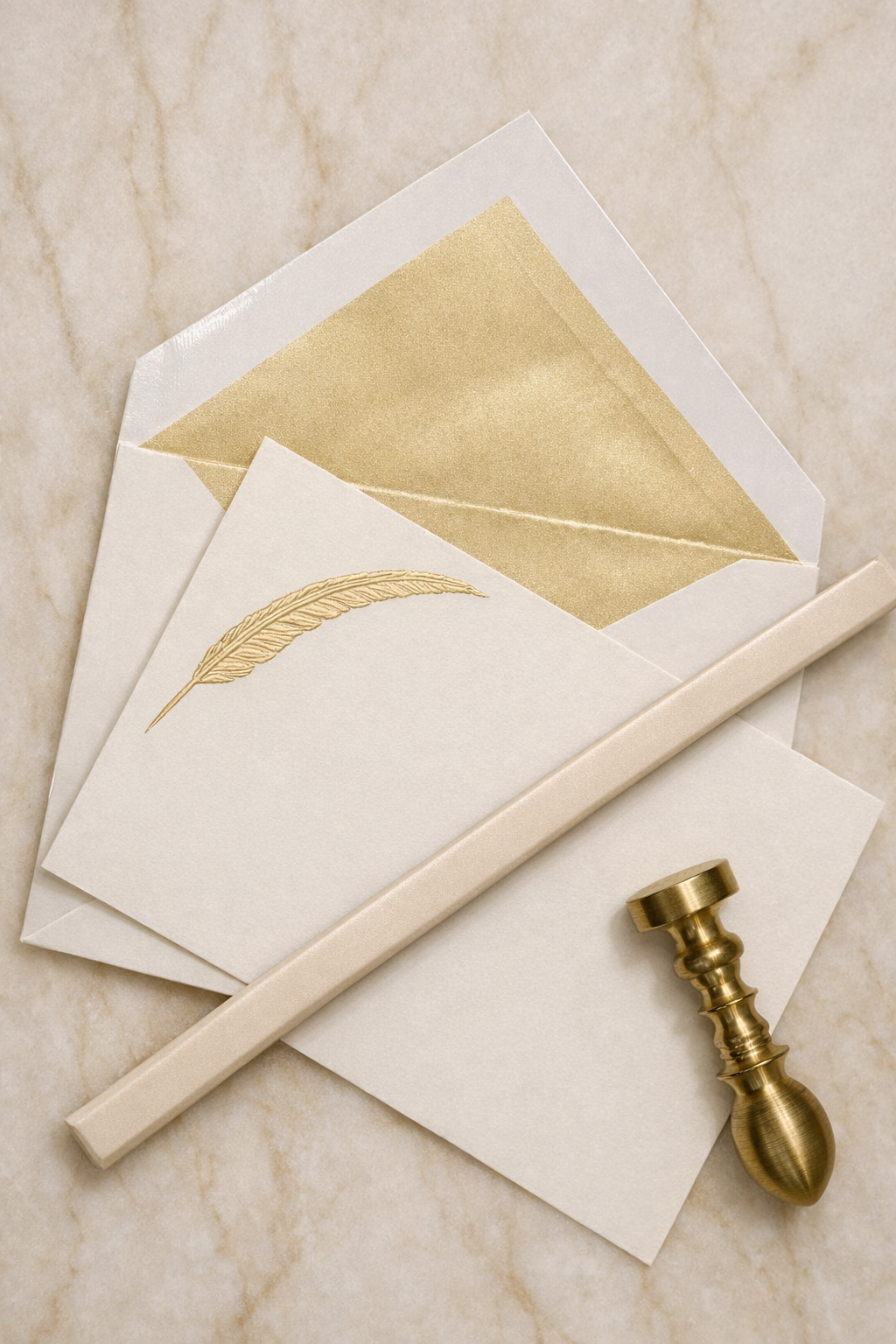Papier blanc avec une plume dorée, enveloppe blanche avec intérieur doré, pièce de décoration dorée en forme de colonne, et une carte blanche
