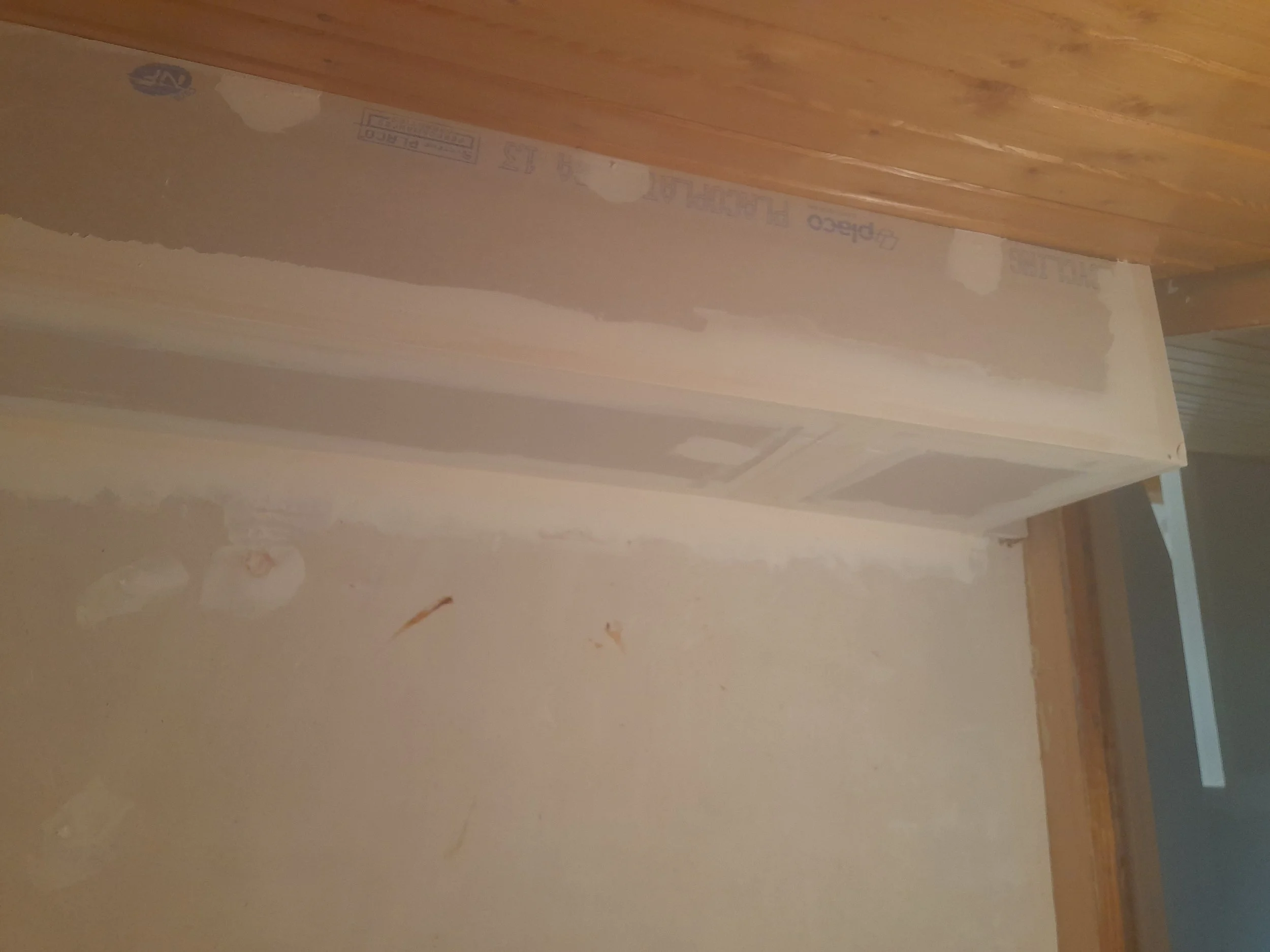 Plan de cloison sèche en phase d'installation sur un plafond en bois, avec des bandes de joint en cours d'application.