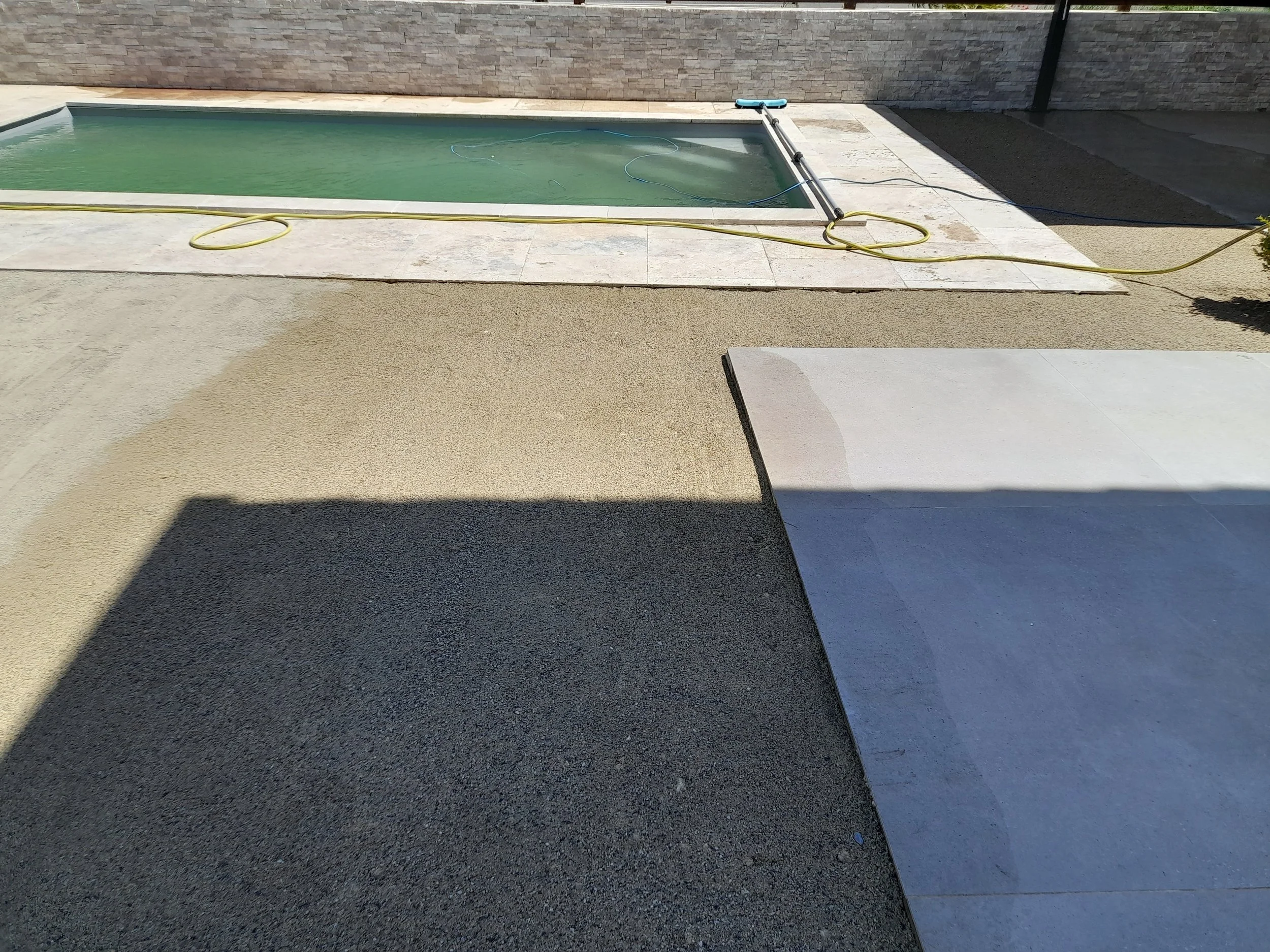 Piscine creusée dans un espace extérieur avec des murs en pierre et un sol pavé, une étape de construction ou de nettoyage en cours