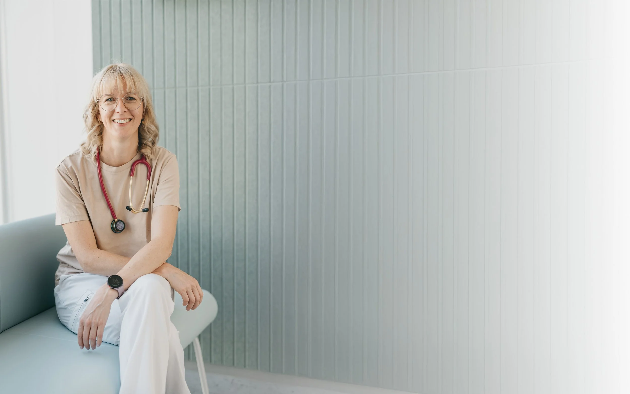 Dr. Judith Hirzenberger, Fachärztin für Allgemein- und Familienmedizin in Linz, sitzt entspannt auf einem Stuhl.