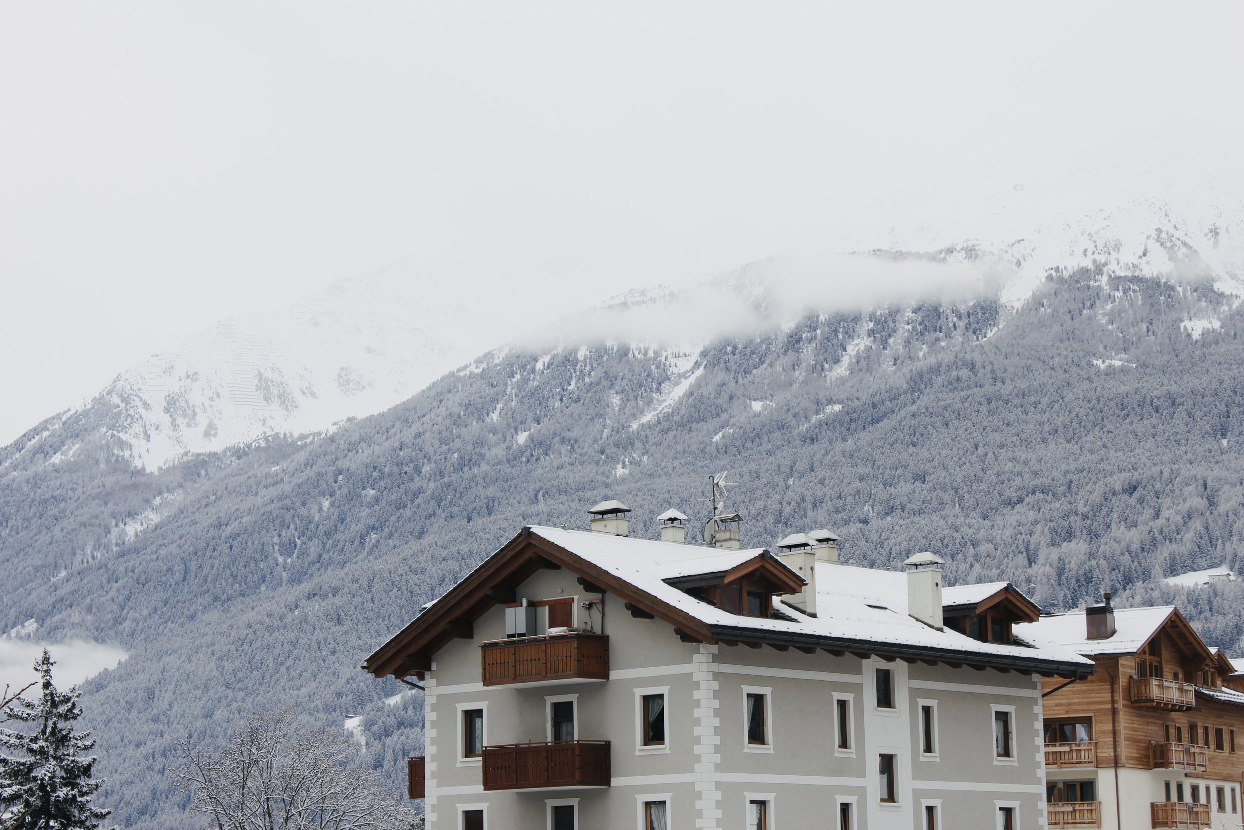 A snowy mountain landscape with a cluster of chalet-style buildings in the foreground.
