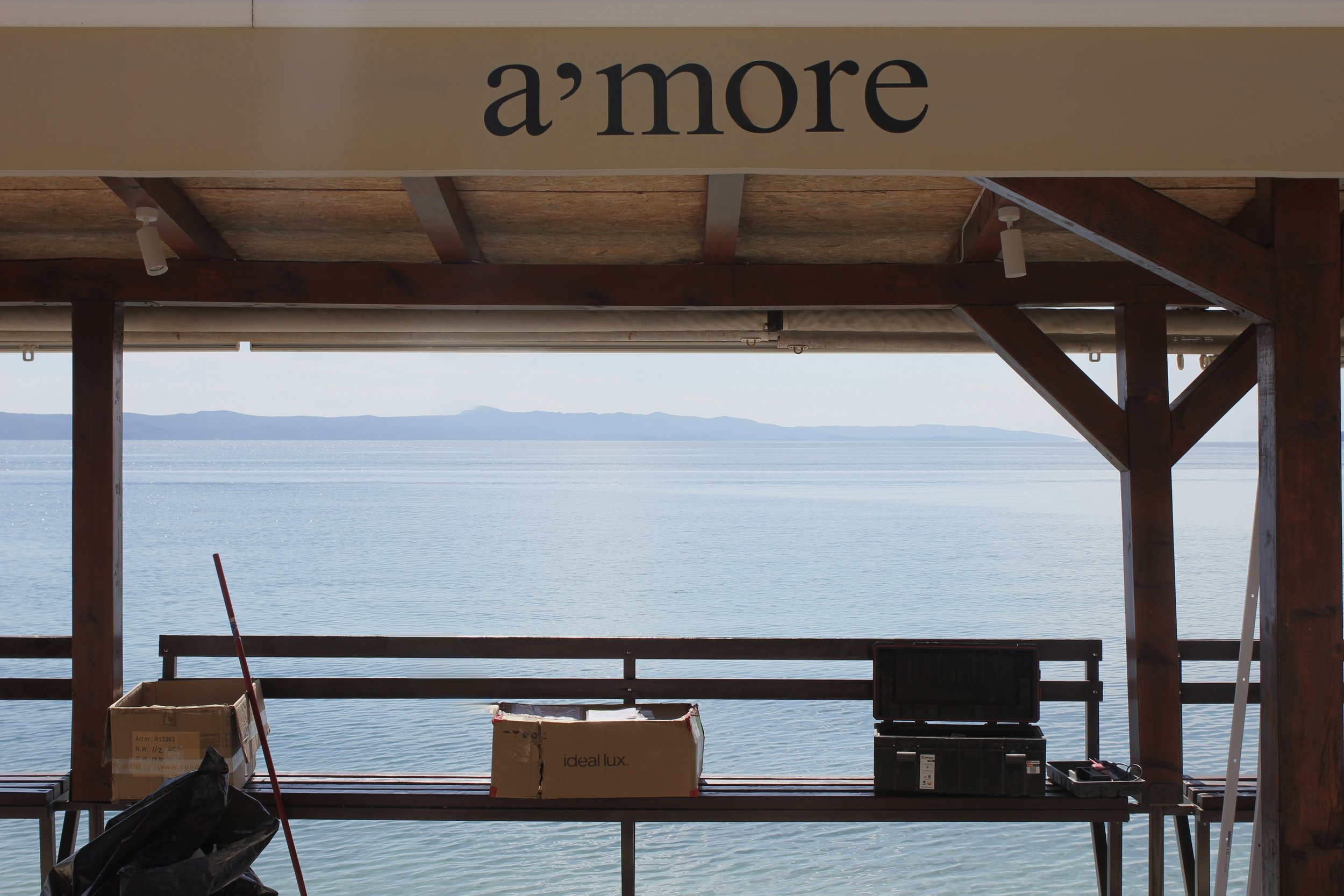 View of the ocean through a wooden structure with a sign that reads 'a’more'.
