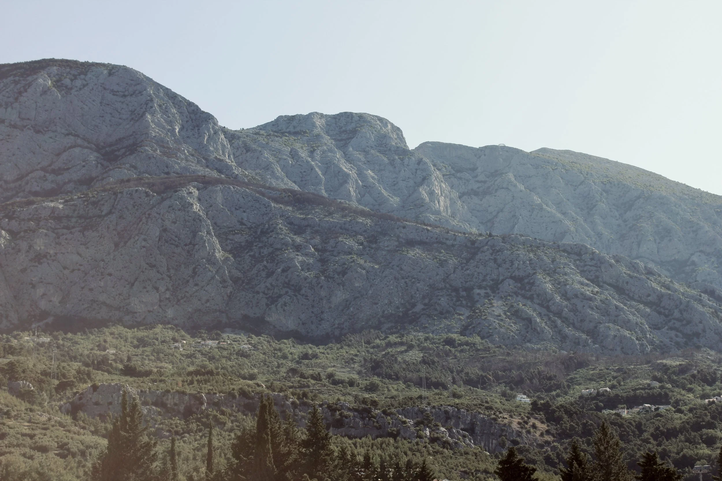 A mountainous landscape with rugged, rocky peaks and green vegetation at the base.