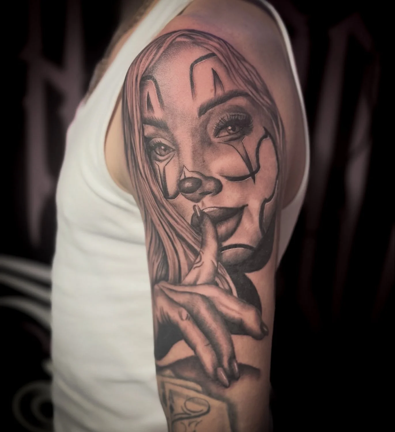 Tattoo of a woman's face with long hair, holding a finger to her lips, on a person's upper arm.