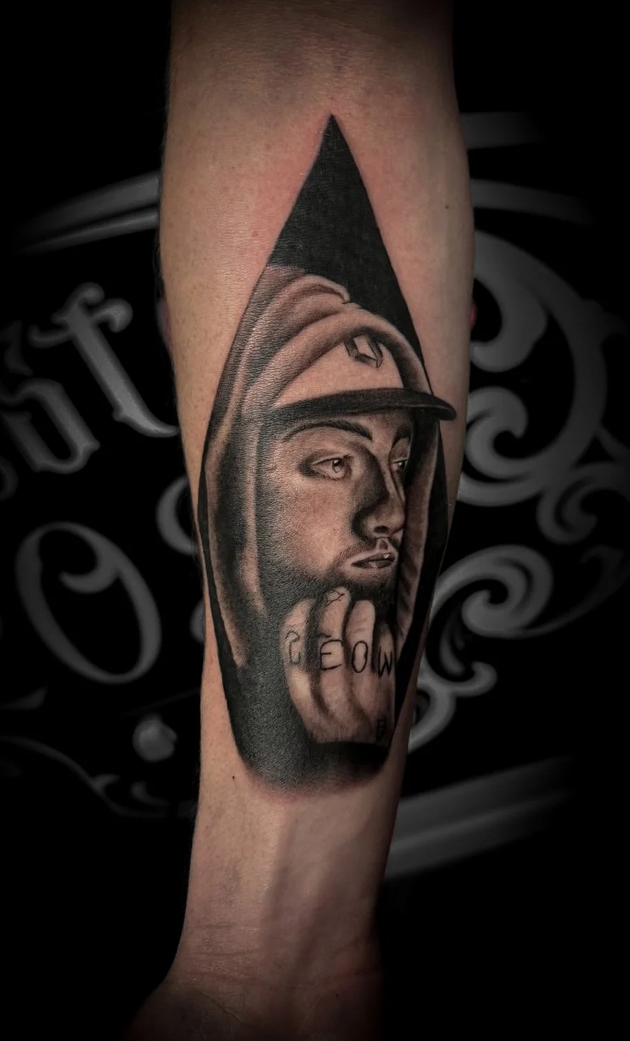 Tattoo of a man with a contemplative expression inside a triangle, on a person's arm.