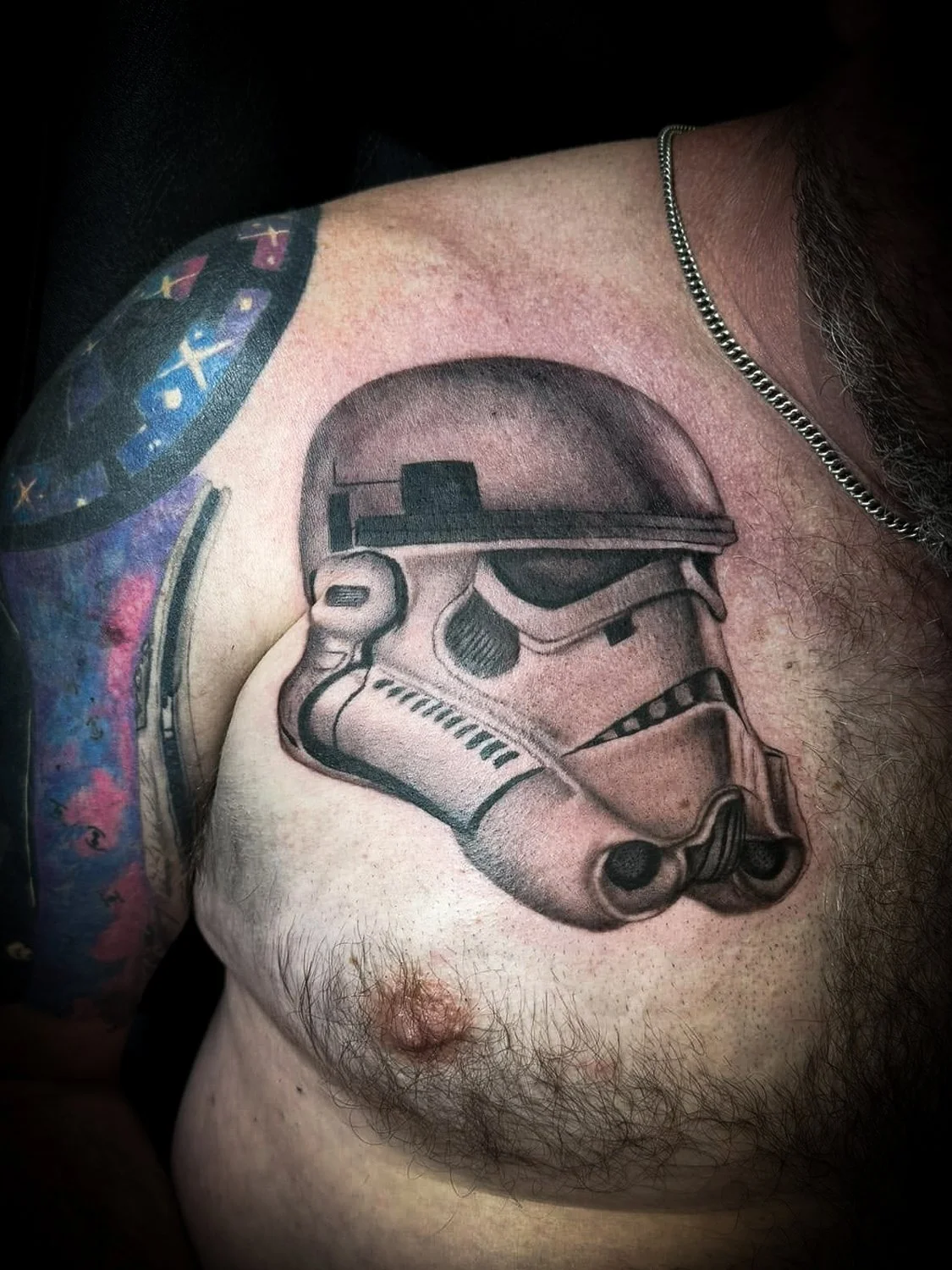 Tattoo of a Stormtrooper helmet from Star Wars on a person's shoulder.