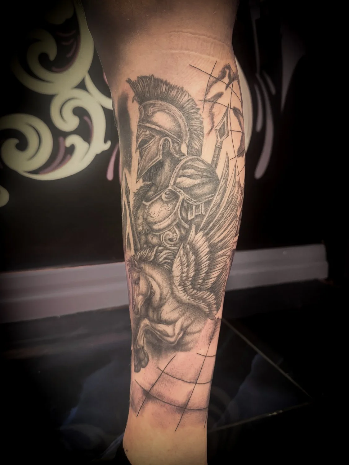 Tattoo of a Roman soldier wearing a helmet, with a spear, and a lion with wings.