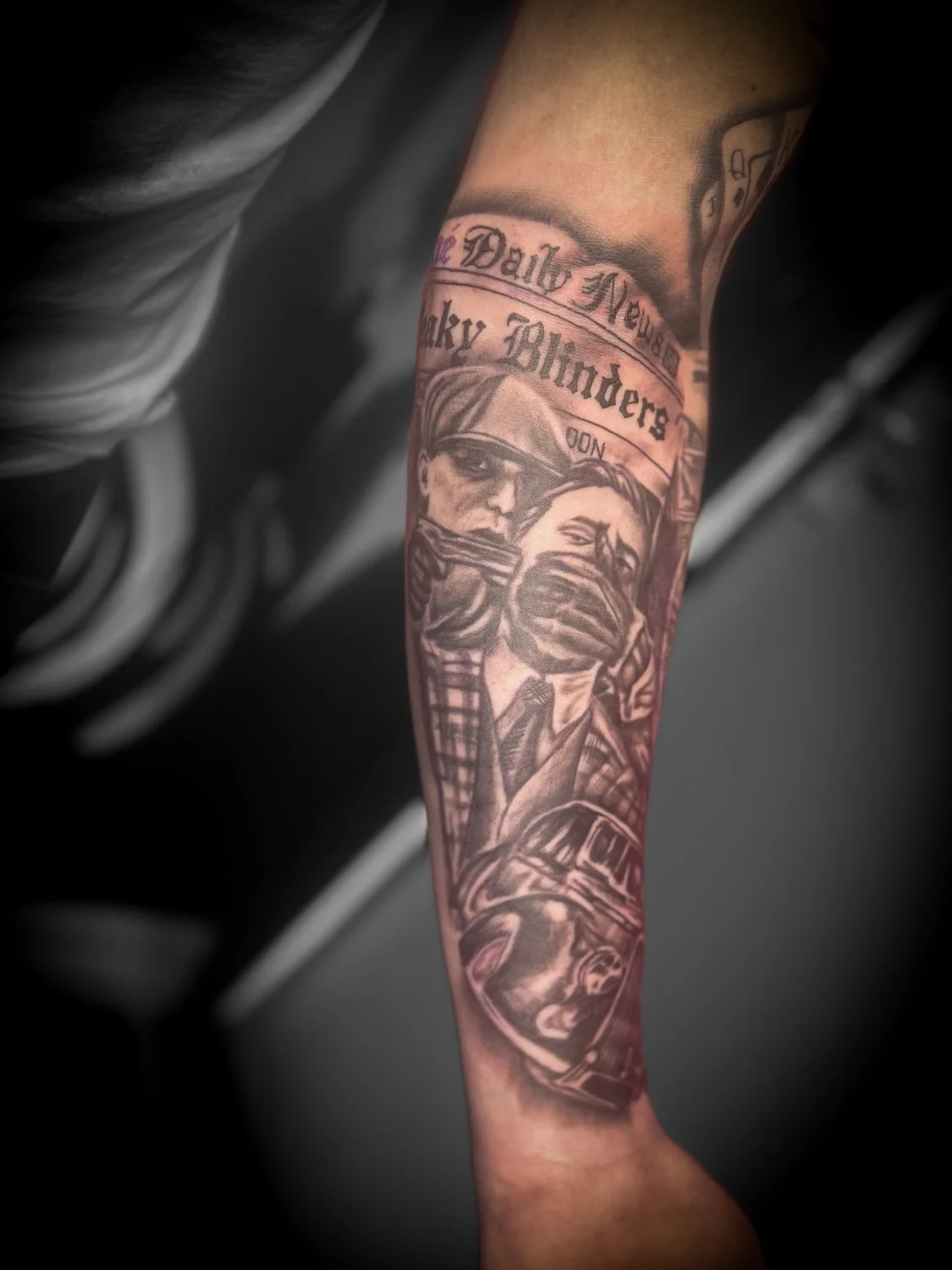 Tattoo on person's arm depicting two individuals with masks, with newspaper headlines above and below.